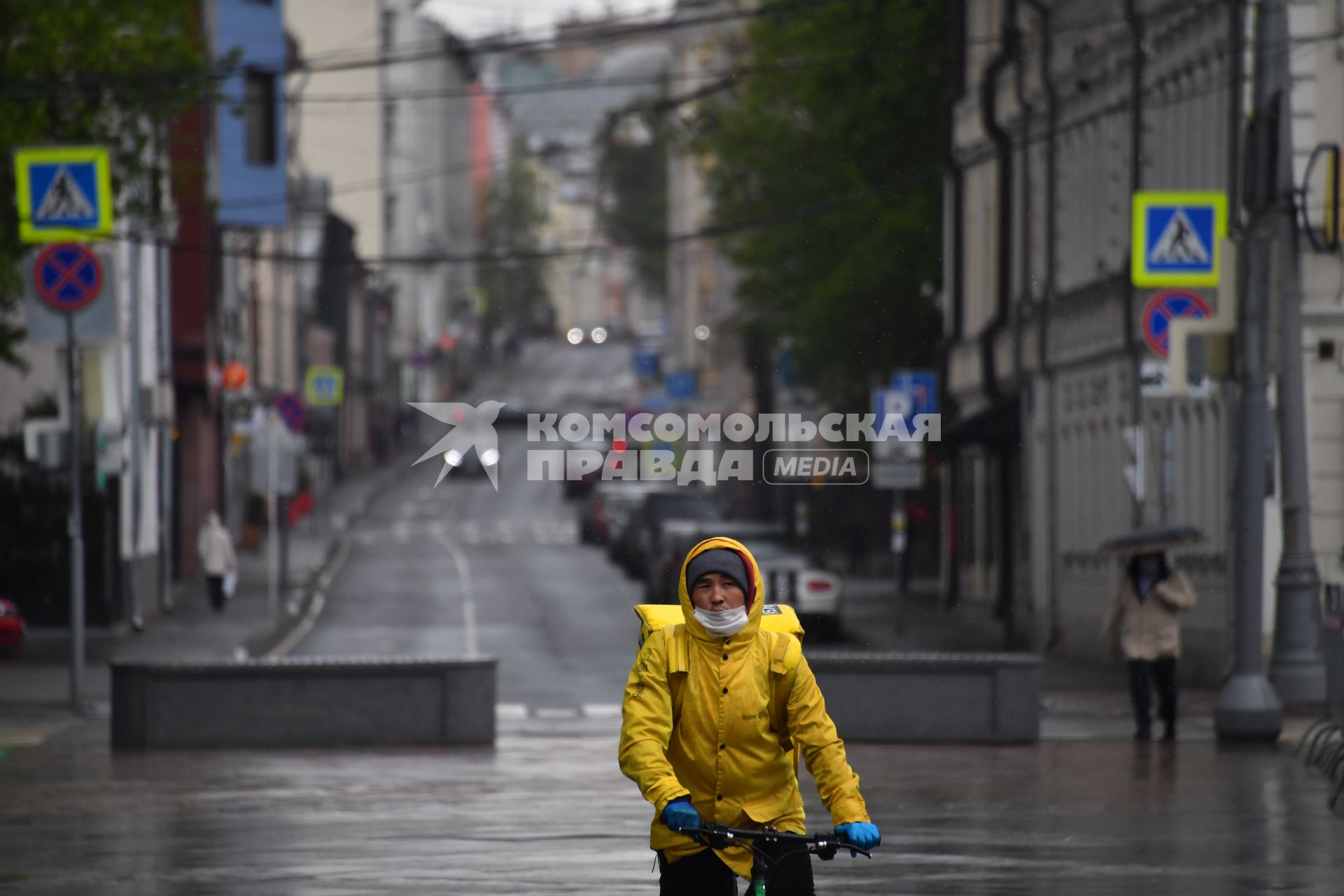 Москва. Сотрудник службы доставки еды в медицинской маске на улице города.