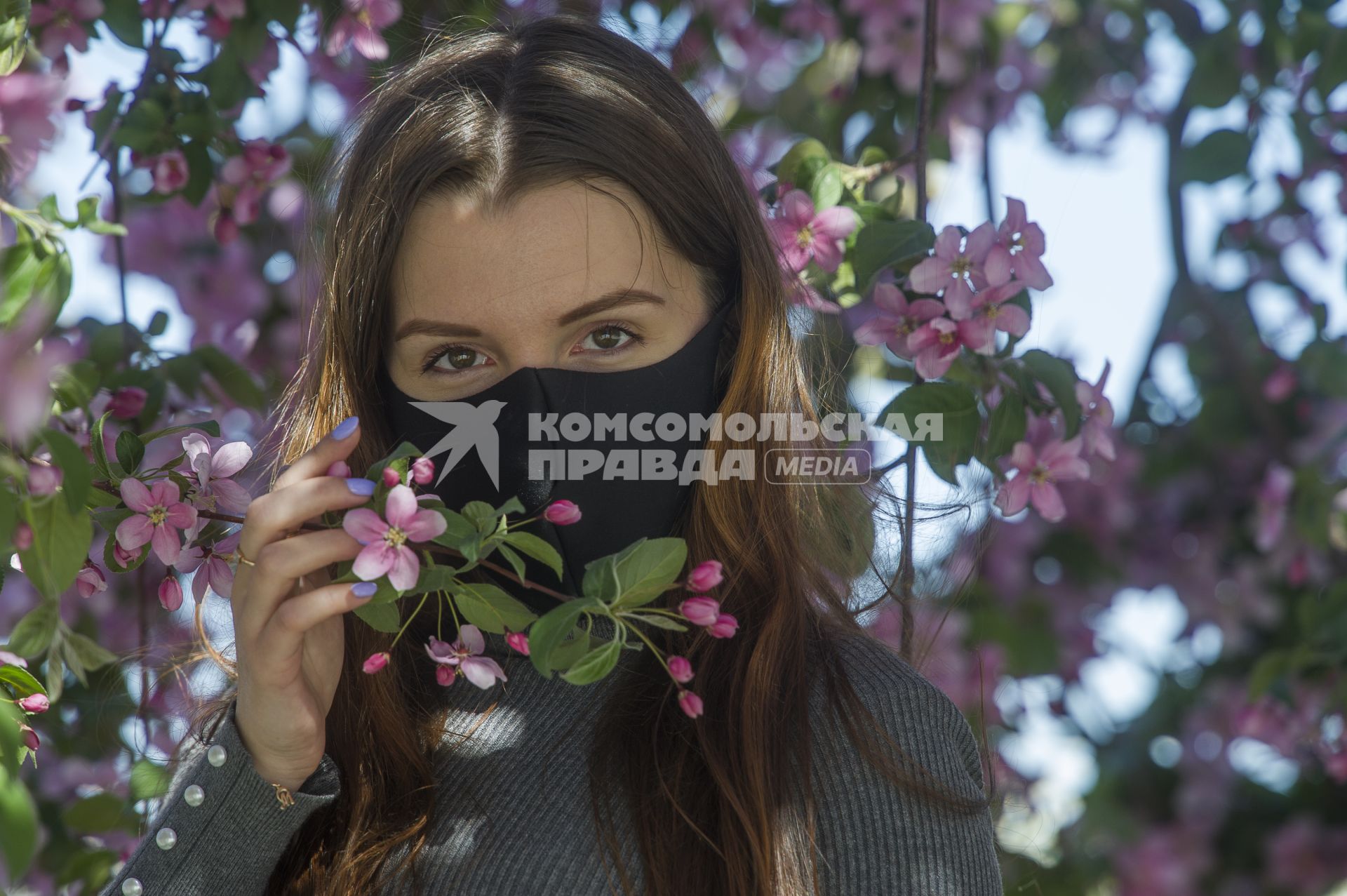 Екатеринбург. Девушка в защитной маске фотографируется у цветущей яблони,  во время режима самоизоляции введеного для нераспространения новой коронавирусной инфекции COVID-19