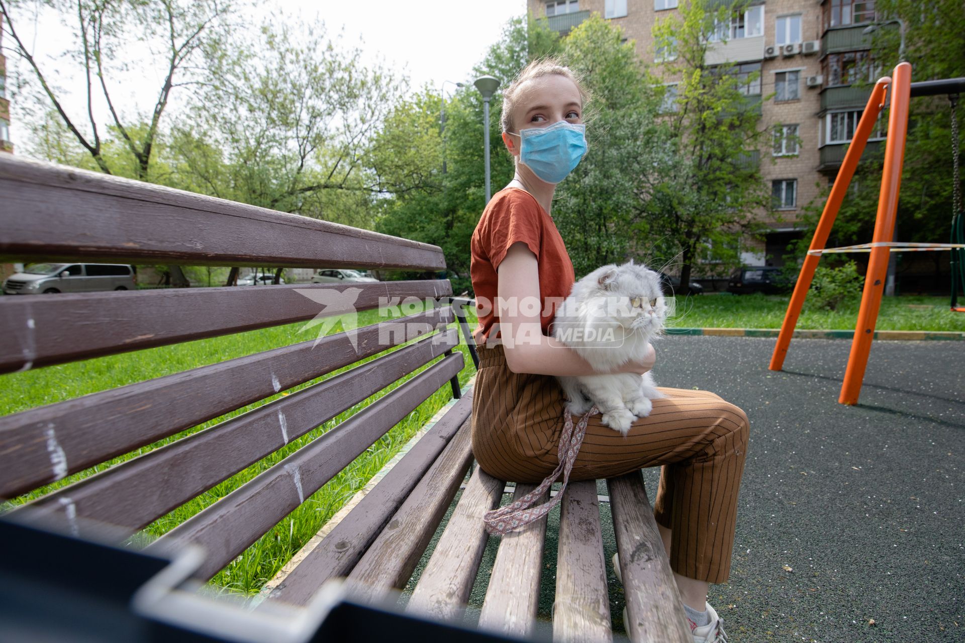 Москва.  Девушка в медицинской маске гуляет с кошкой во дворе.