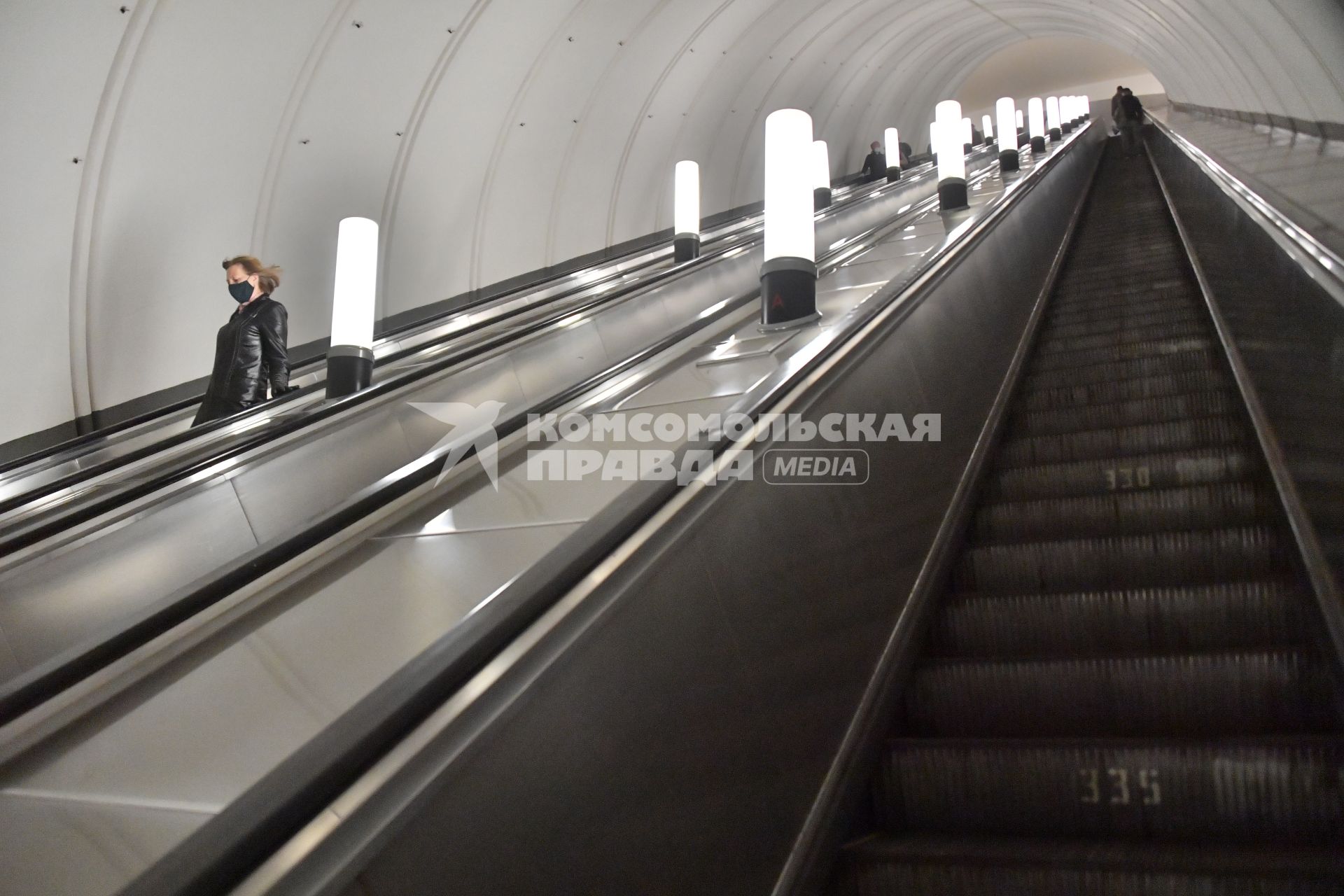 Москва.  Пассажиры в медицинских масках на эскалаторе метро.