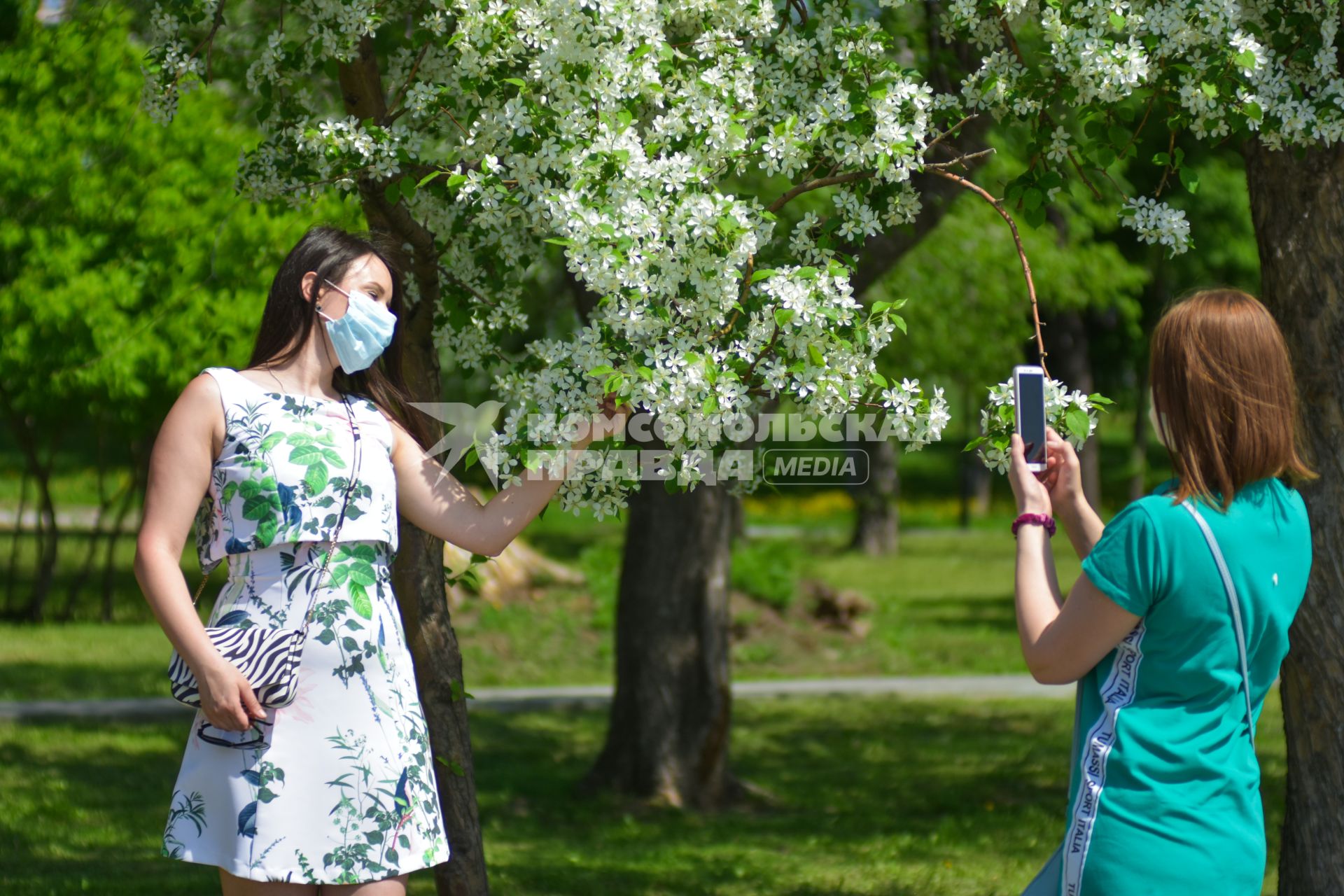 Новосибирск. Девушка в медицинской маске около цветущего дерева.
