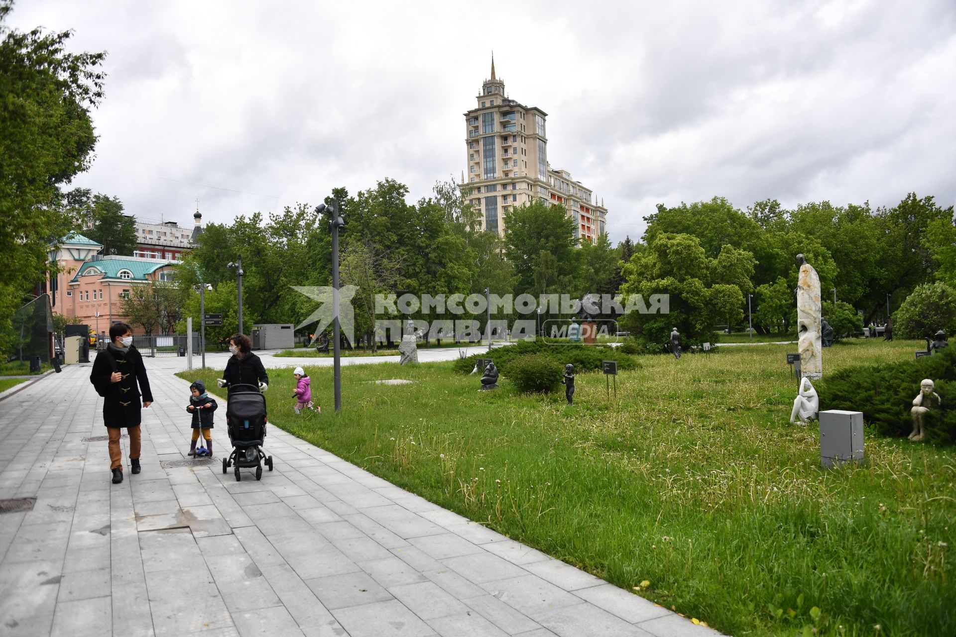 Москва.  Женщина и мужчина с детьми гуляют в парке Музеон.