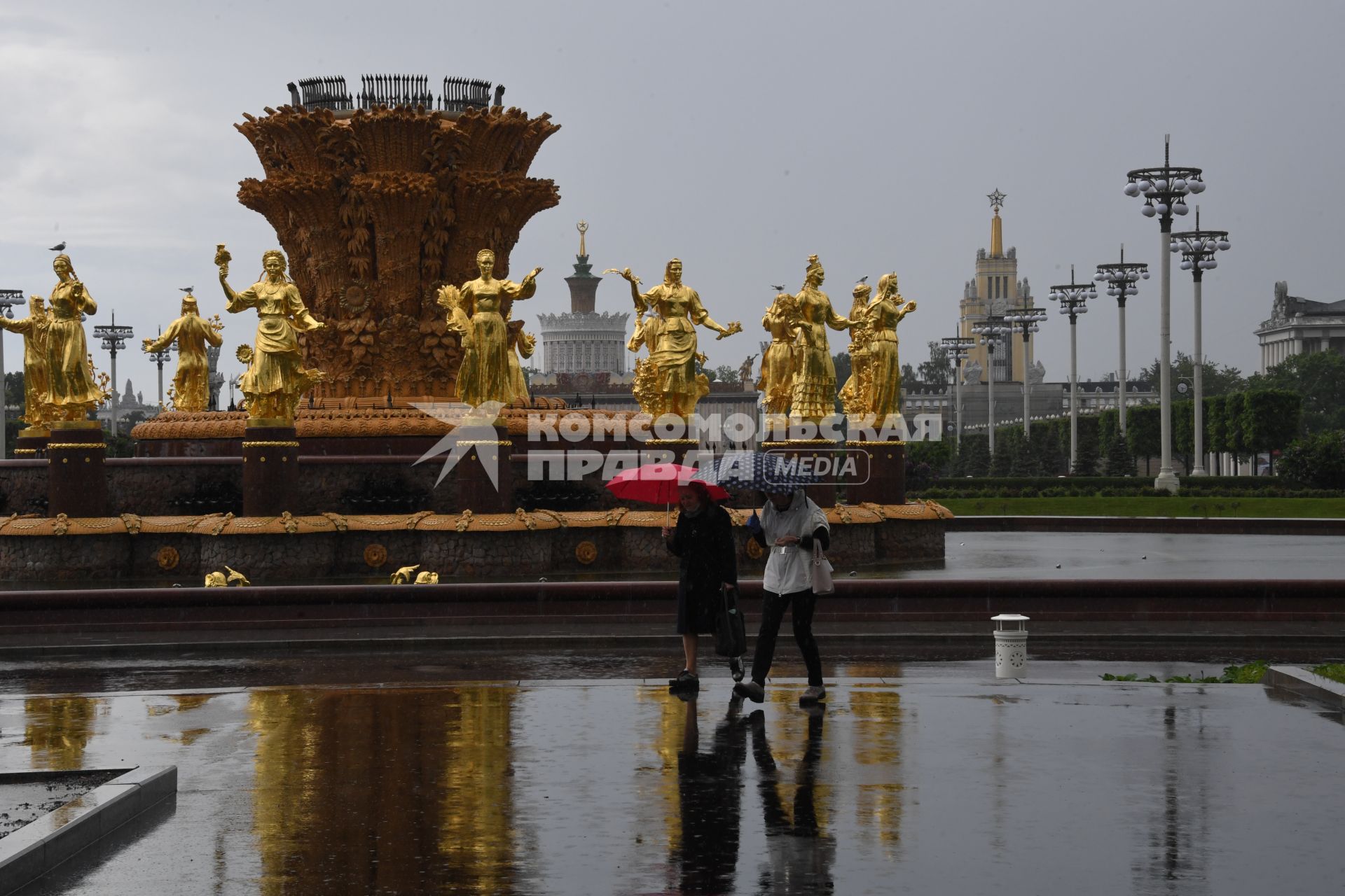 Москва.  Прохожие гуляют у фонтана `Дружба народов`на ВДНХ во время дождя.