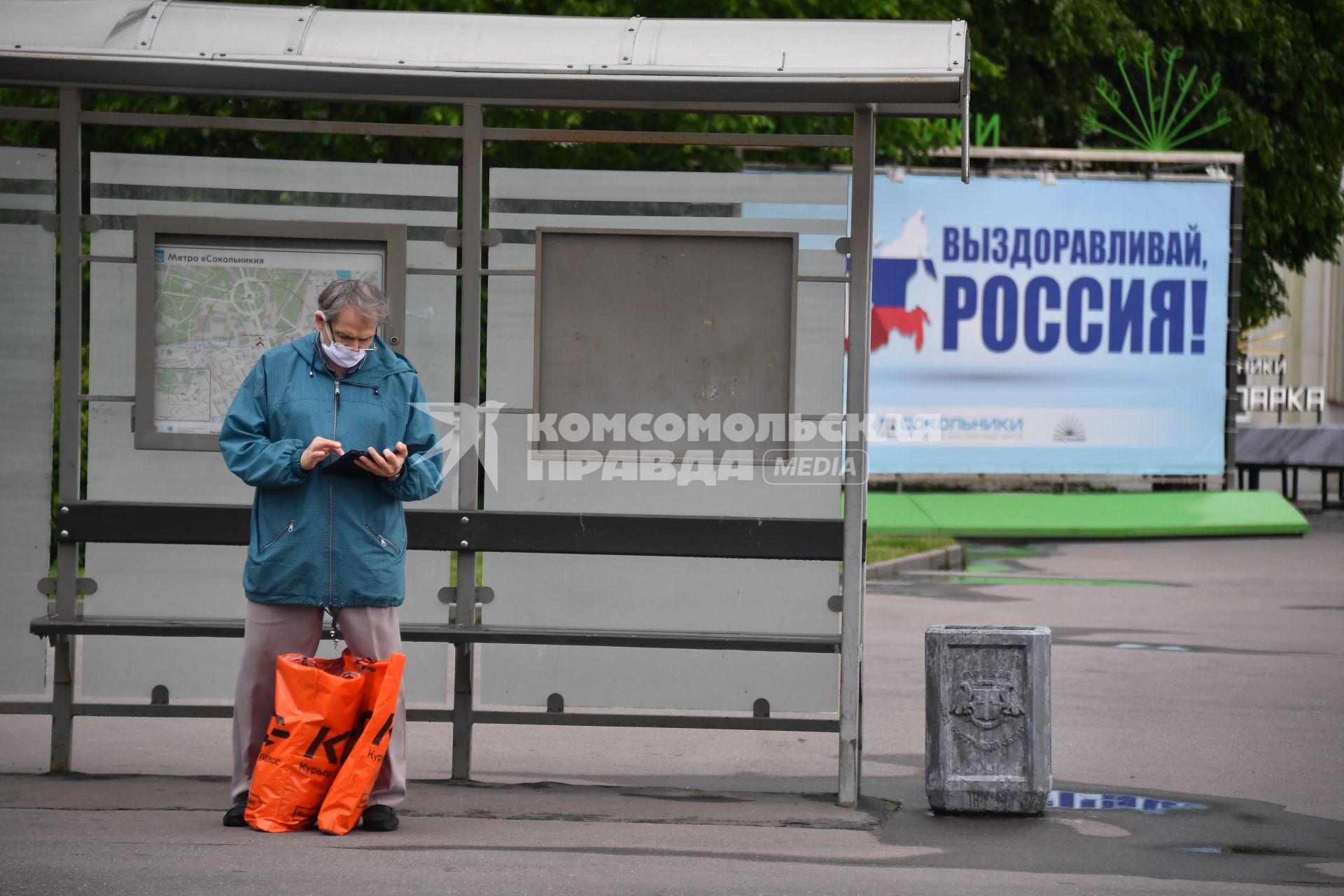 Москва.  Мужчина в медицинской маске на остановке общественного транспорта.