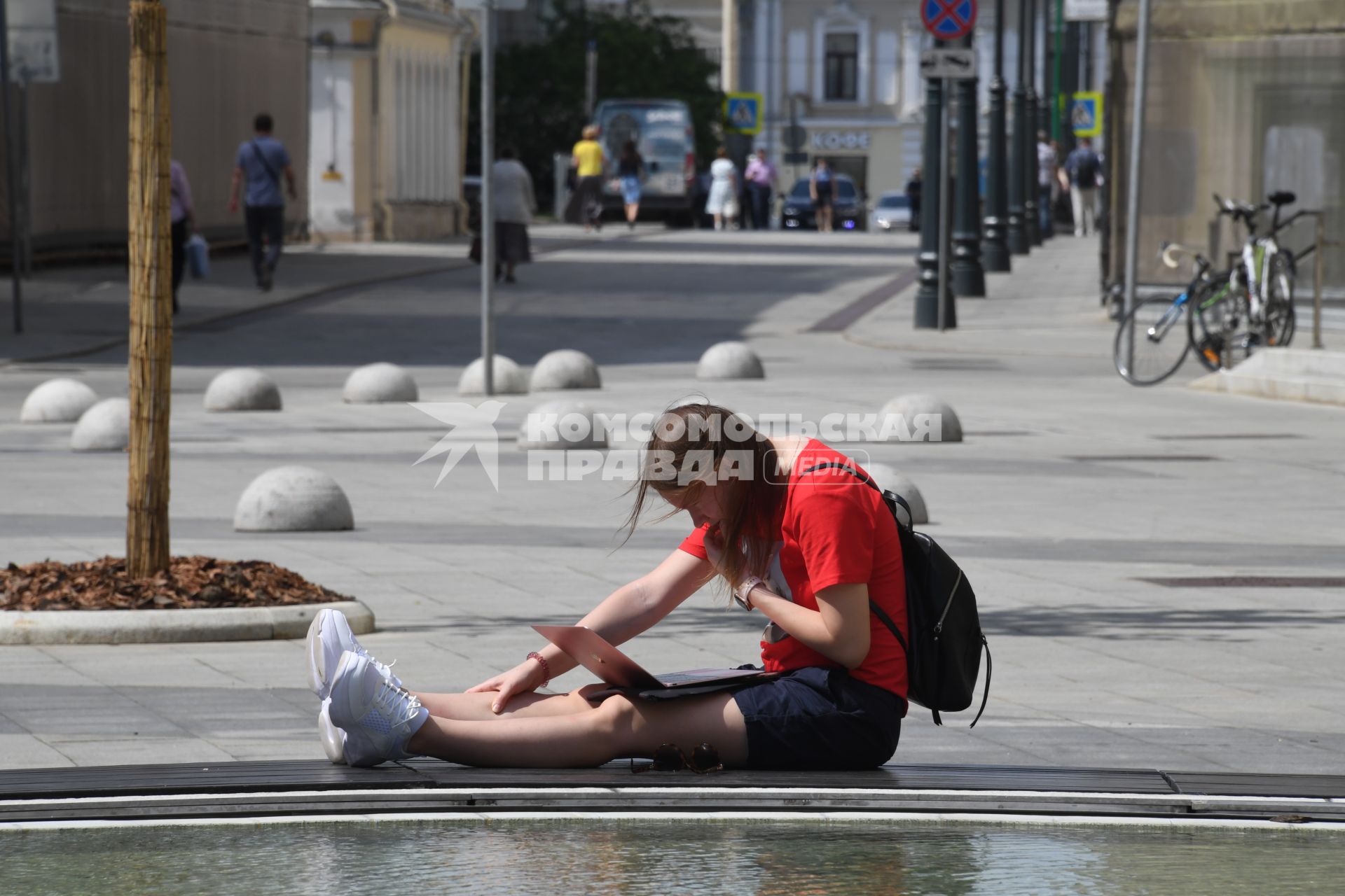 Москва.  Девушка сидит у фонтана после отмены режима самоизоляции в городе.