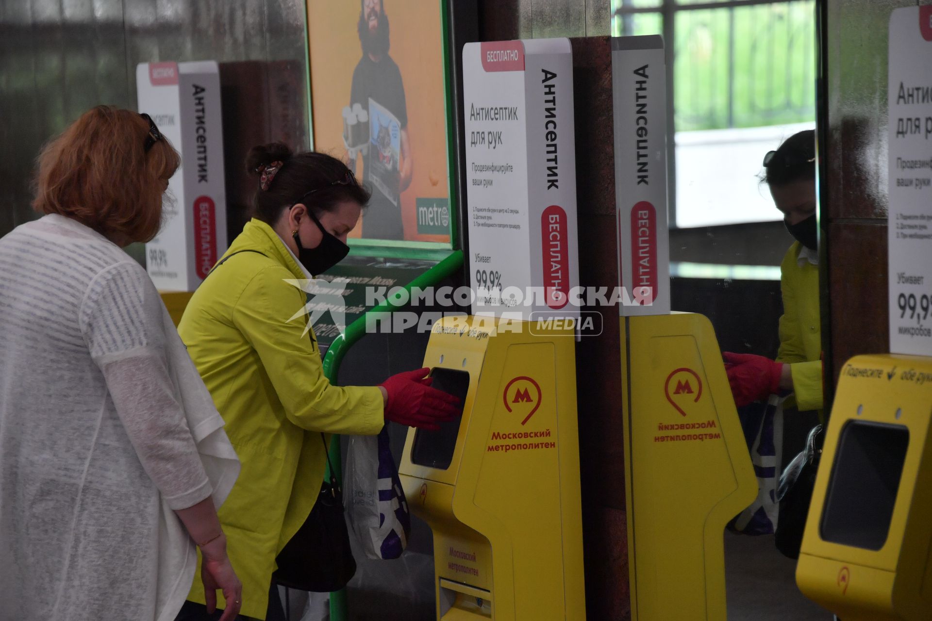 Москва.  Пассажиры метрополитена  в медицинских масках обрабатывают руки антисептиком.