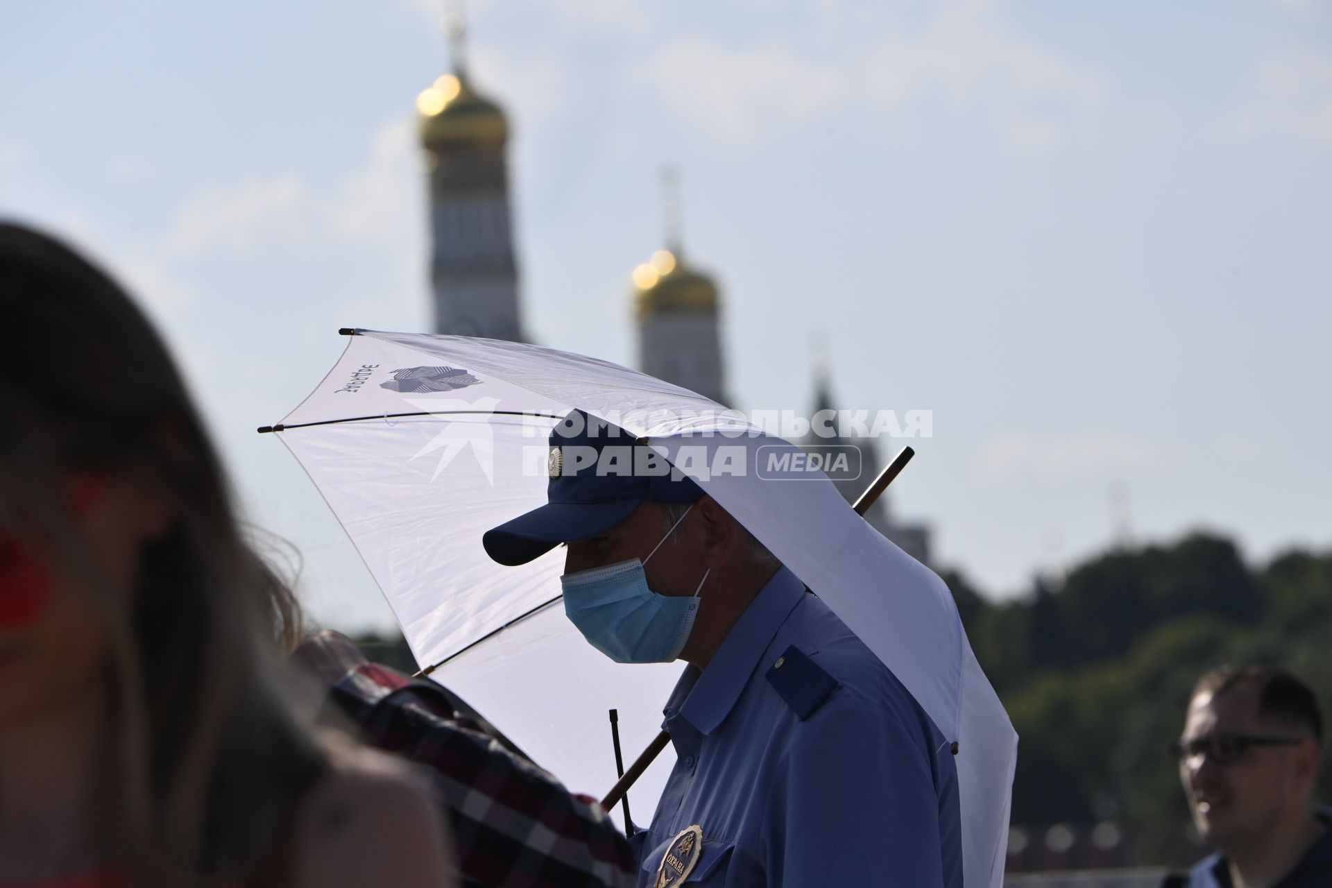 Москва. Мужчина под зонтом в медицинской маске в парке Зарядье.