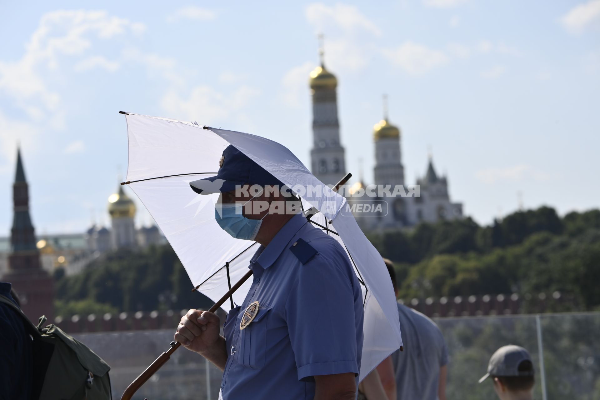 Москва. Мужчина под зонтом в медицинской маске в парке Зарядье.