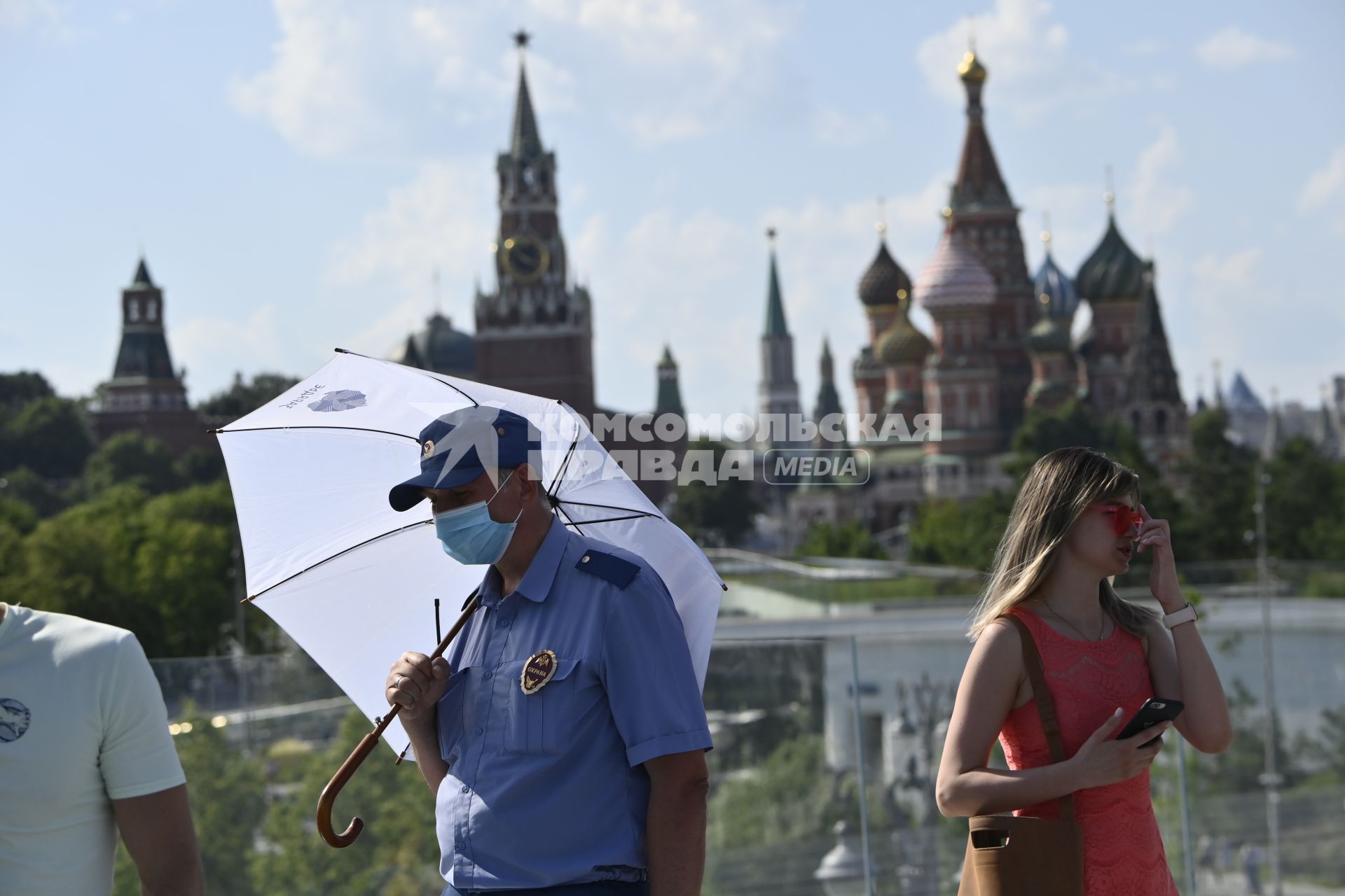 Москва. Мужчина под зонтом в медицинской маске в парке Зарядье.