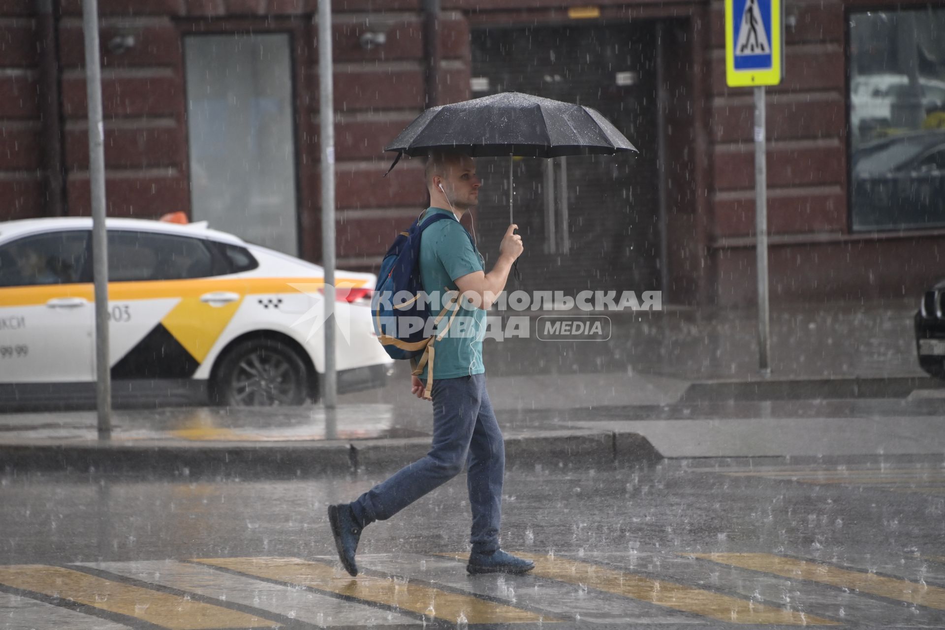 Москва.  Мужчина под зонтом на пешеходном переходе.