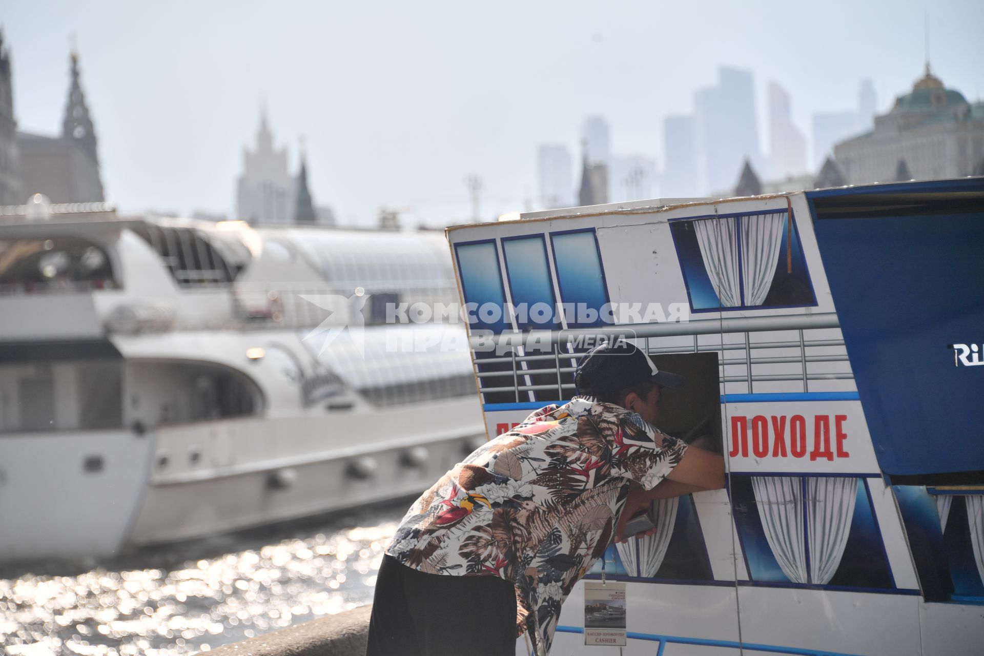 Москва. Мужчина покупает билет на прогулку по Москва-реке.