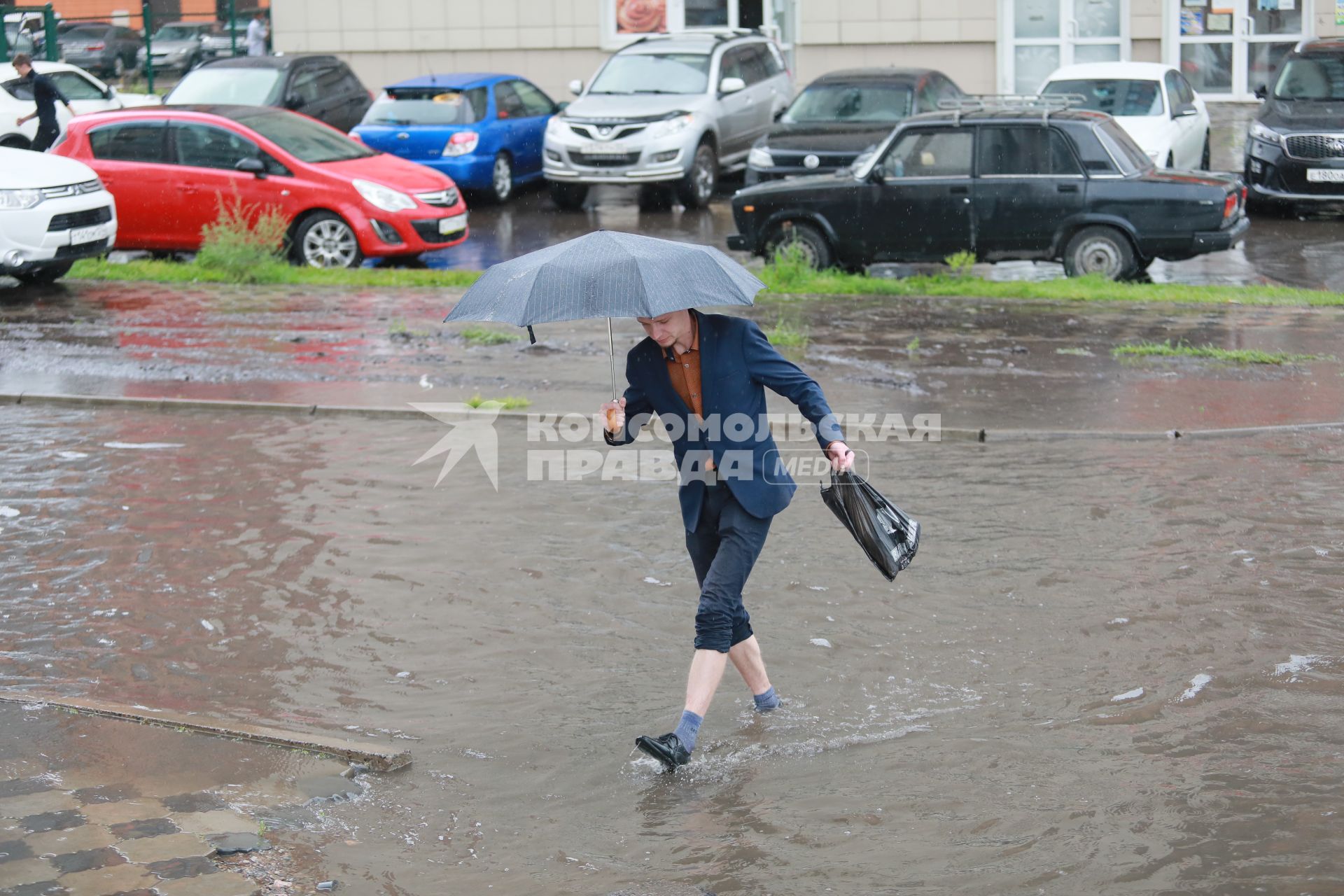 Красноярск. Пешеходы идут по лужам во время дождя.