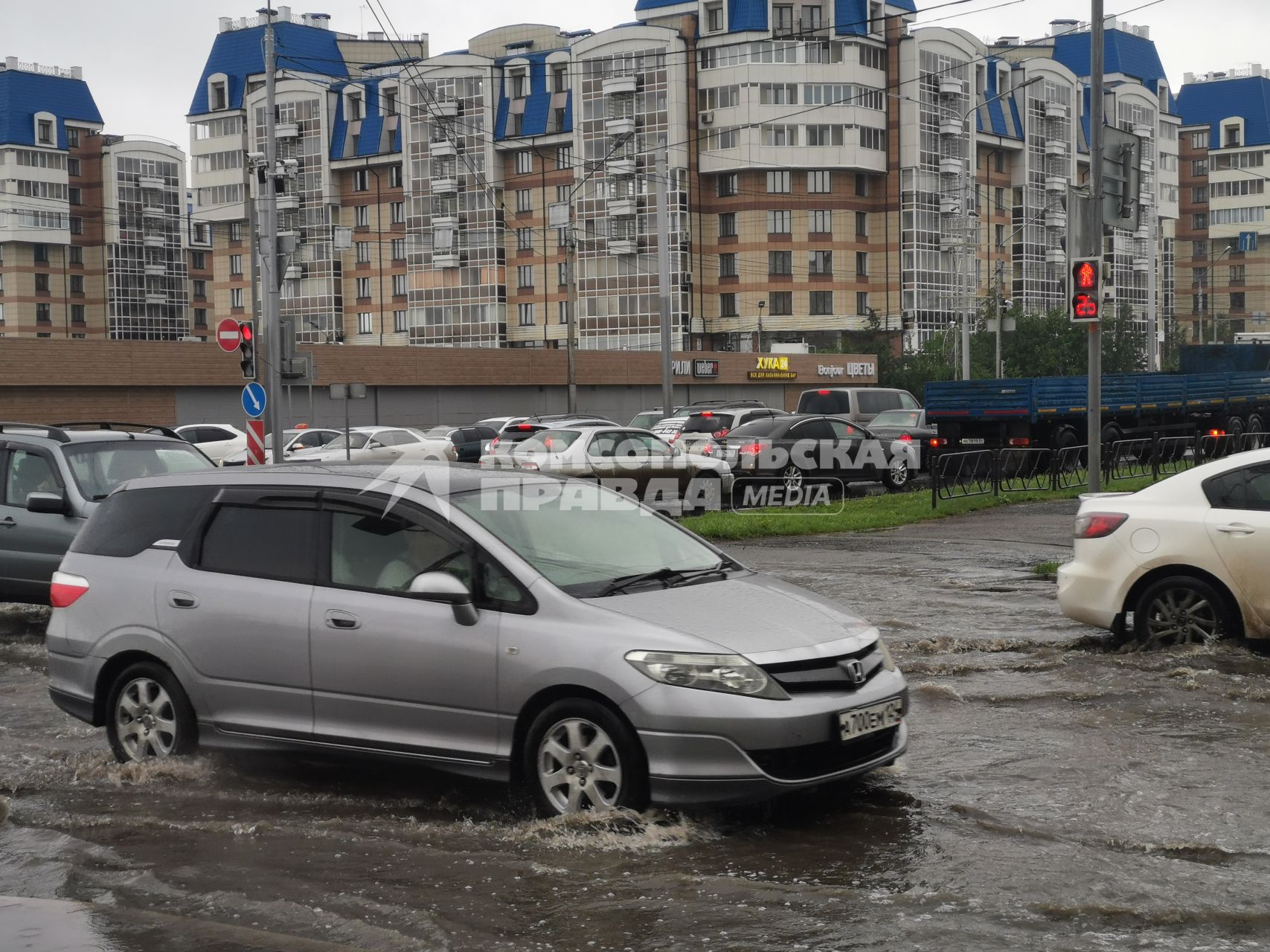 Красноярск. Машины едут по лужам во время дождя.