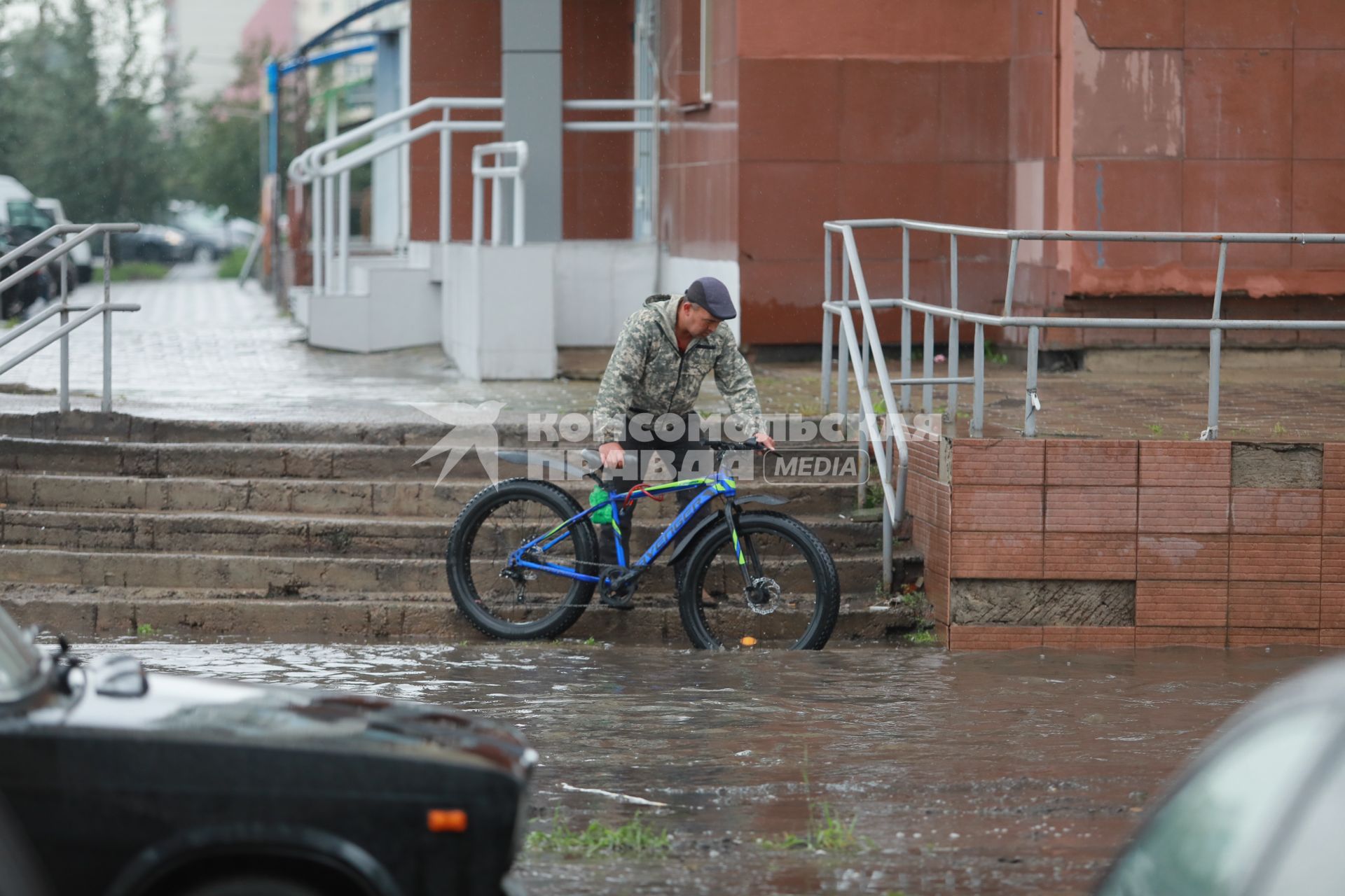 Красноярск. Велосипедист на улице во время дождя.