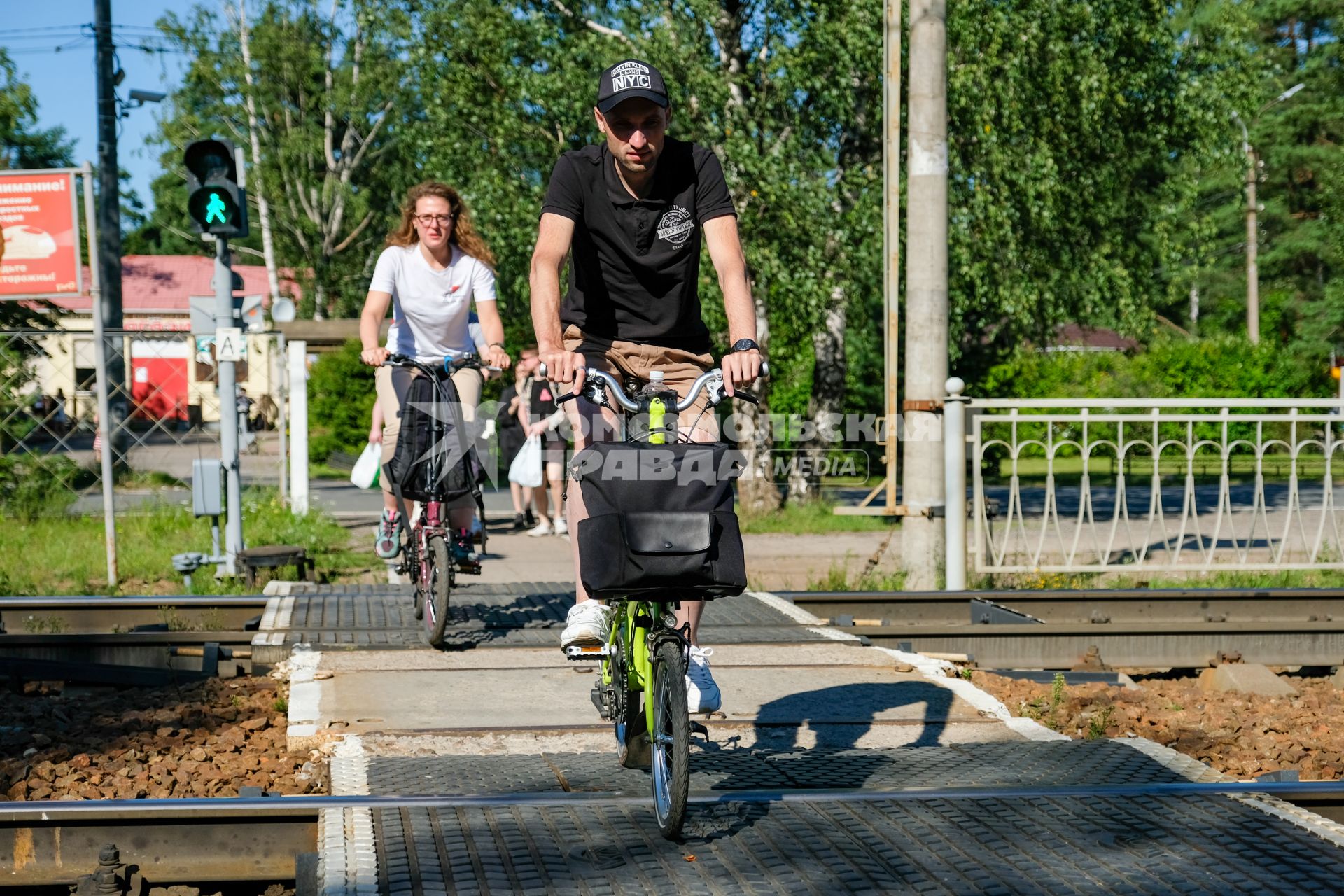 Санкт-Петербург.   Мужчина и женщина на велосипедах переезжают железную дорогу.