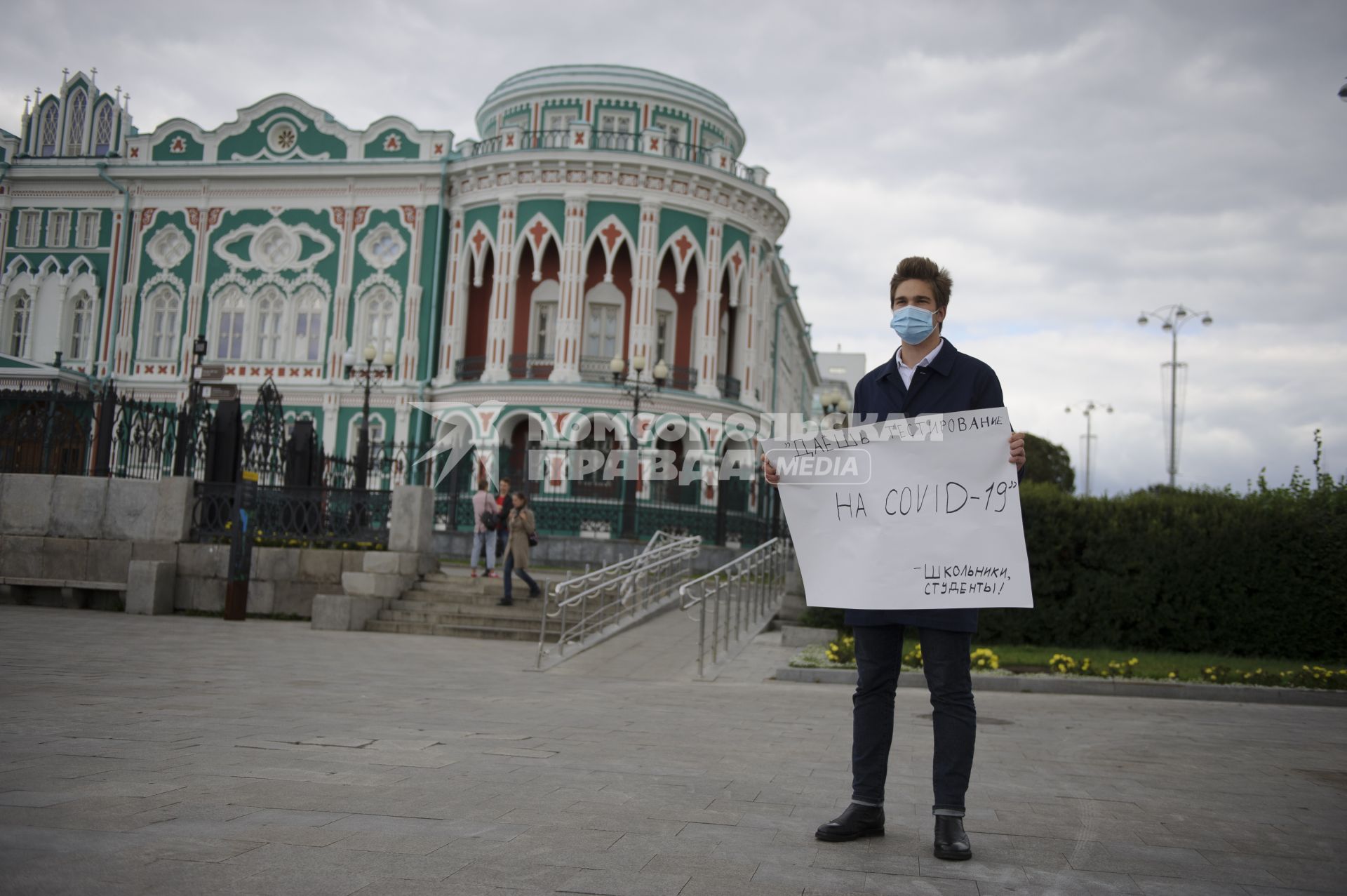 Екатеринбург. Парень в медицинской маске с плакатом призывающим провести тестирование школьников и студентов на COVID-19 у здания резиденции губернатора Свердловской области