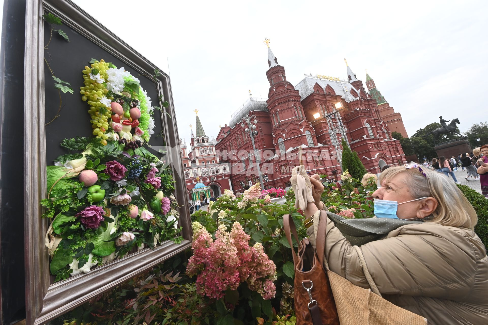 Москва.   Женщина фотографирует  время посещения арт-объекта `Тропа ботанического сада`, расположенного между Манежной площадью и площадью Революции, на праздничных гуляниях в День города.