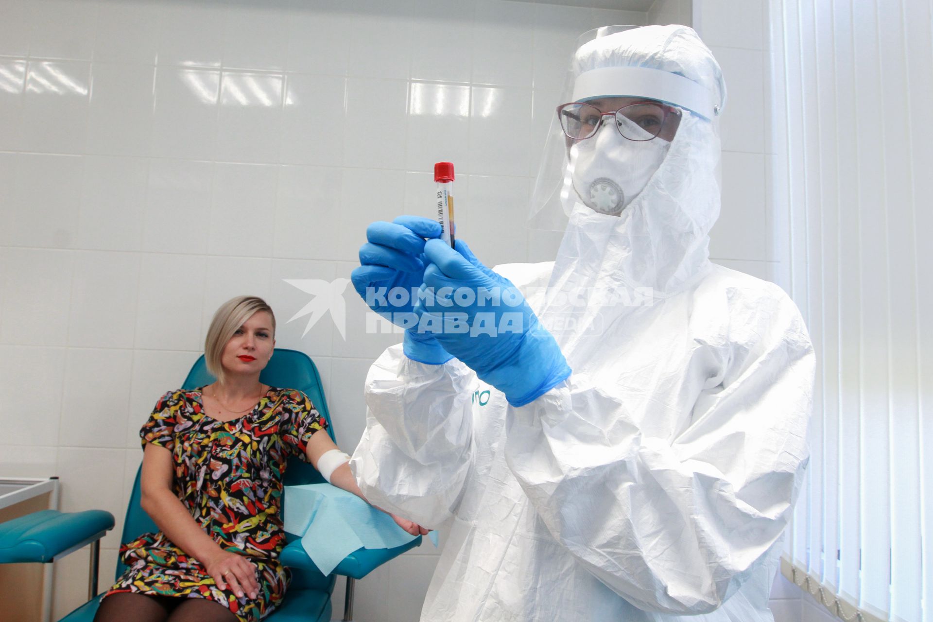 Иркутск.  Медицинский работник в защитном костюме держит в руках пробирку с биоматериалом  в городской поликлинике.
