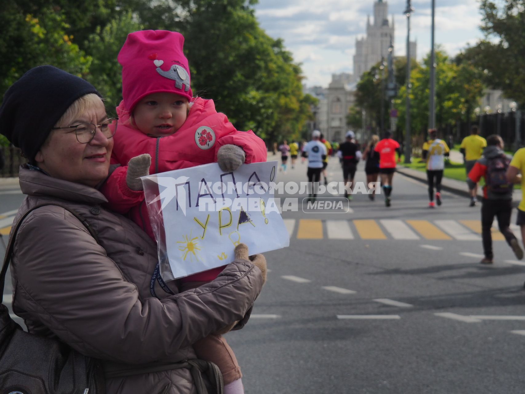 Москва.  Женщина с ребенком во время забега участников Московского марафона - 2020.