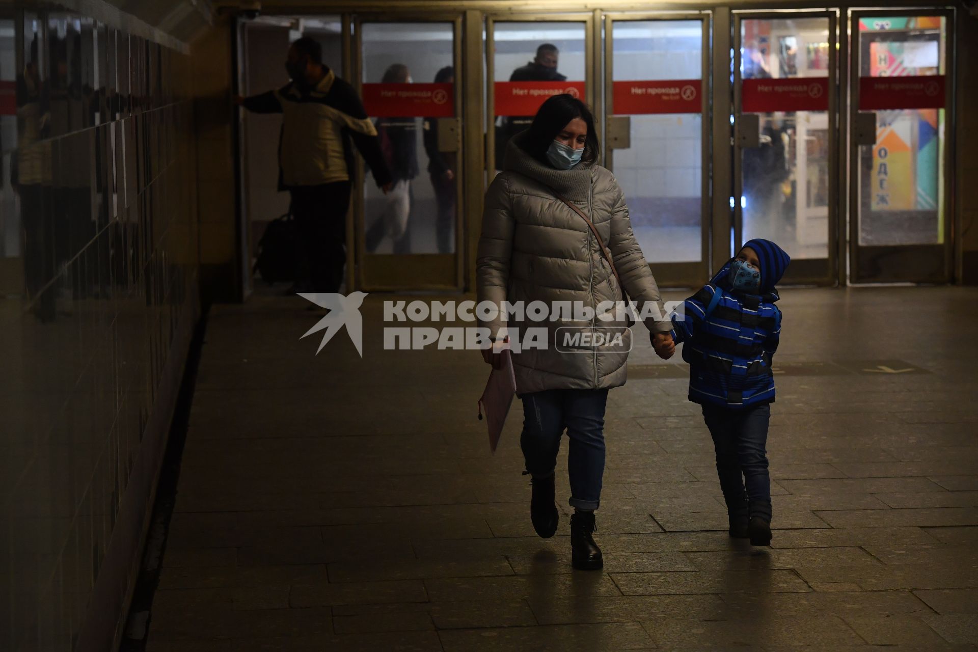 Москва. Женщина с ребенком в медицинских масках в подземном переходе метро.