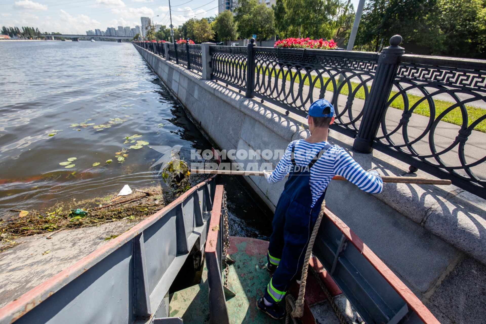 Москва.  Матрос мусоросборщика  `МС-1` собирает мусор с поверхности реки.