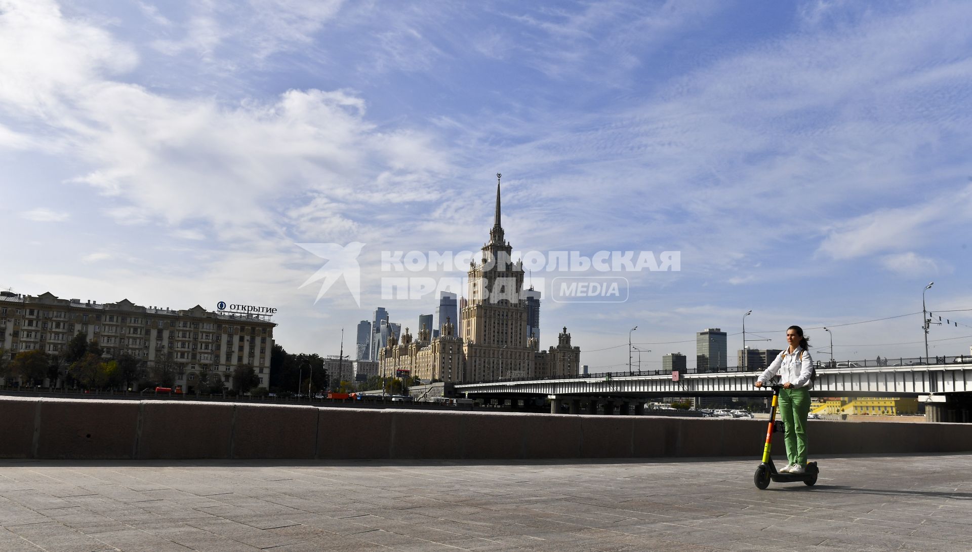 Москва.   Девушка катается на самокате  на набережной.