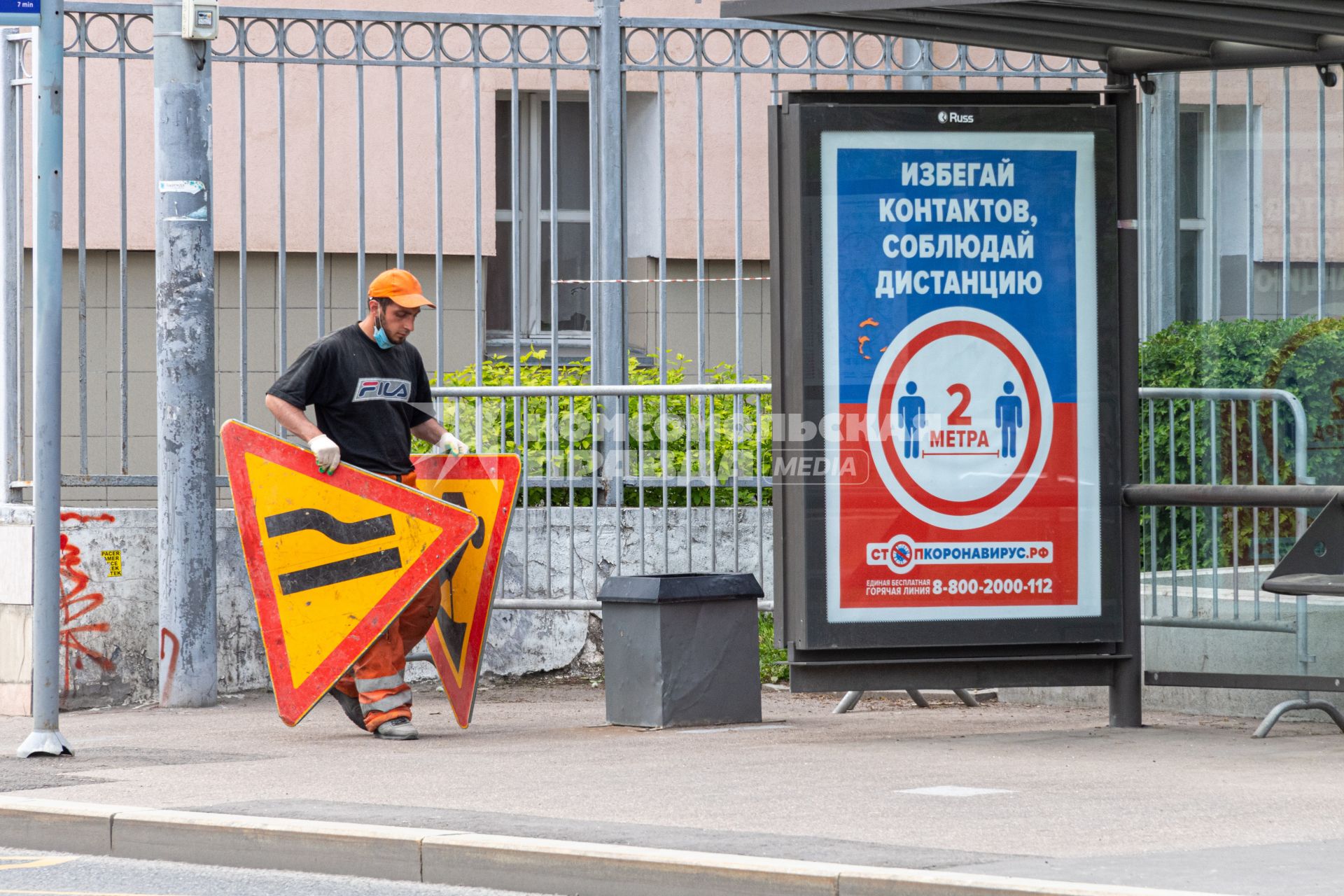 Москва. Пилон `Избегай контактов, соблюдай дистанцию` на остановке общественного транспорта, рядом с которой ведутся дорожные работы.