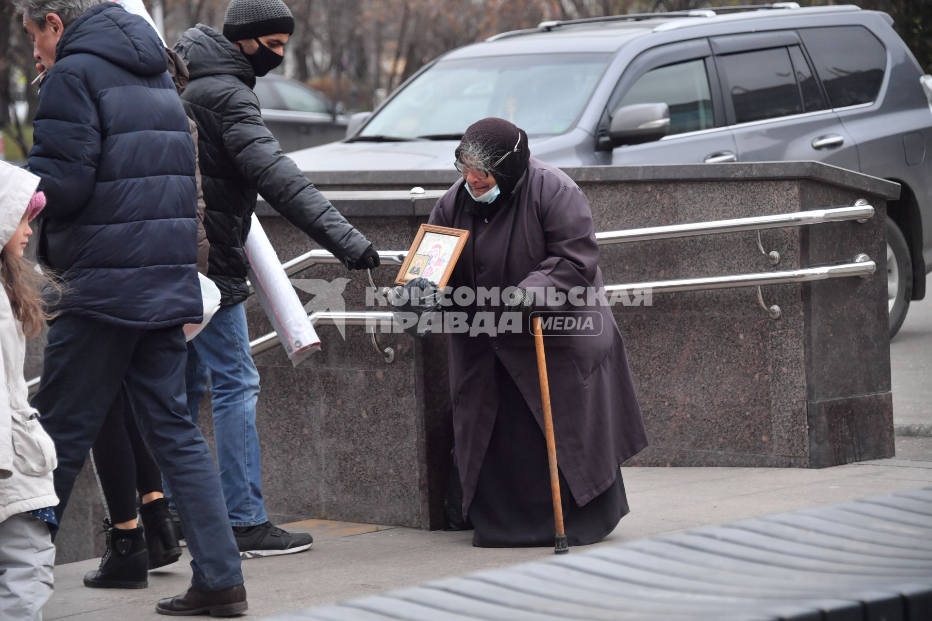 Москва. Пожилая женщина  просит милостыню у входа в метро.