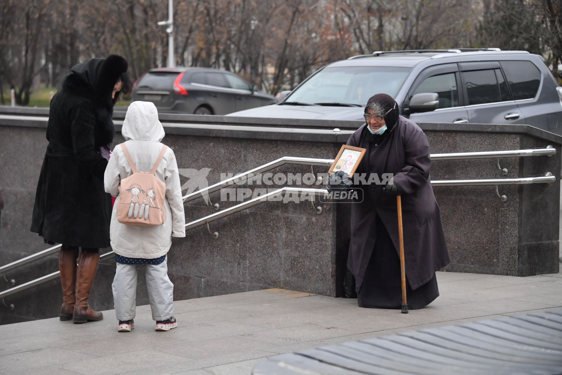 Москва. Пожилая женщина  просит милостыню у входа в метро.