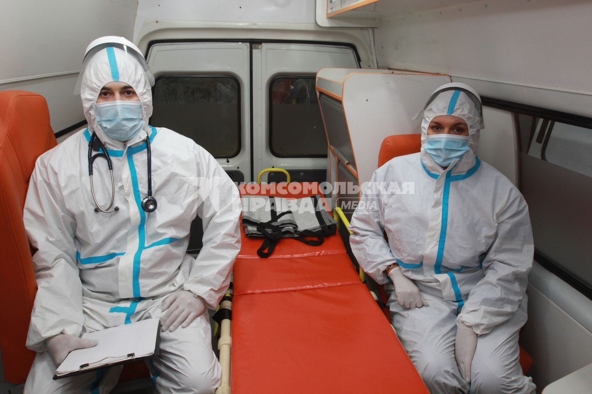 Иркутск. Медицинские работники в защитных костюмах в автомобиле скорой помощи.
