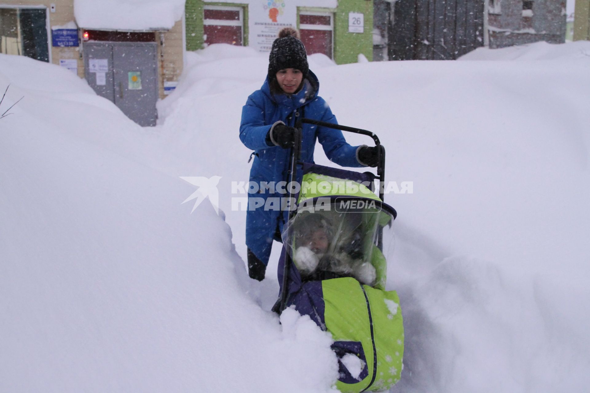 Норильск. Девушка с ребенком в коляске во время прогулки после снегопада.