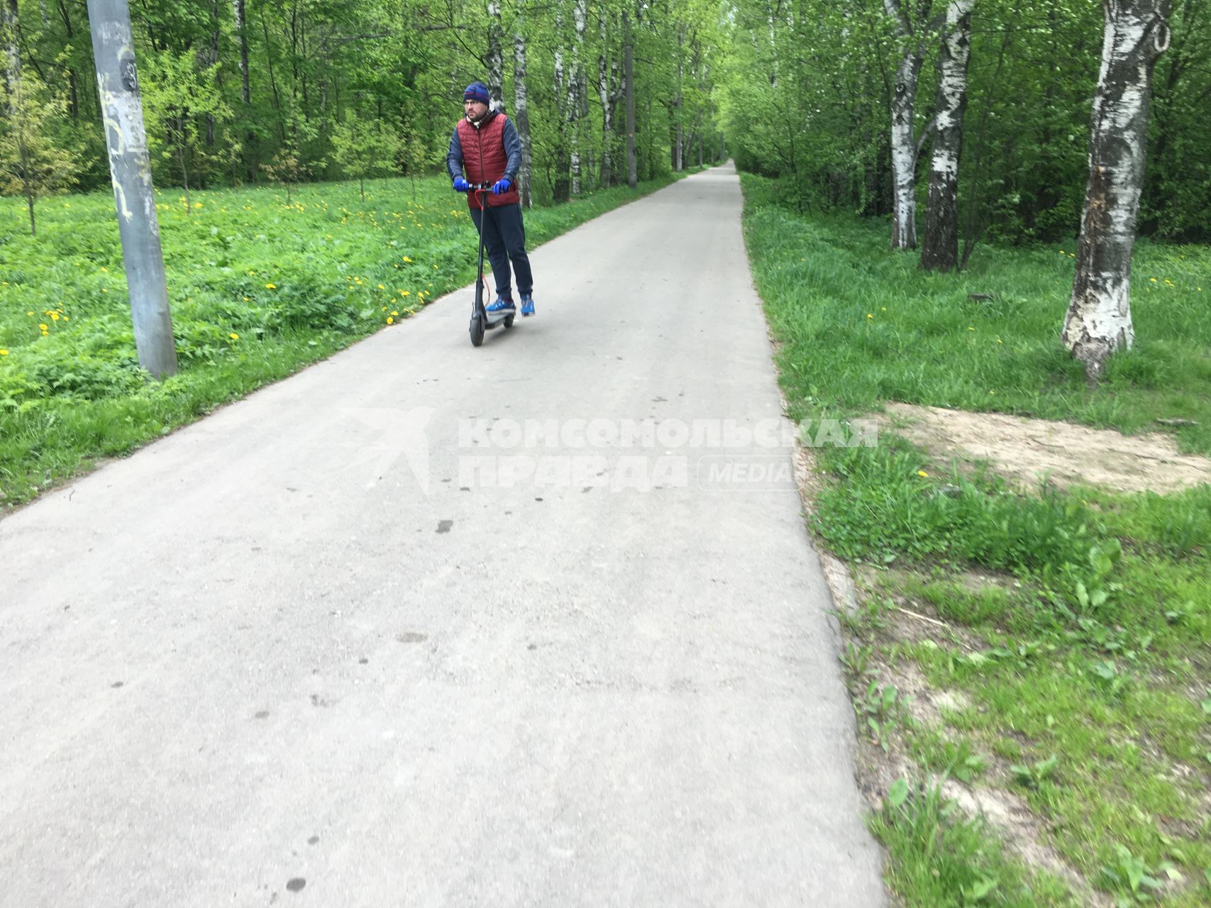 Москва.   Мужчина едет на самокате  в Кусковском лесопарке.