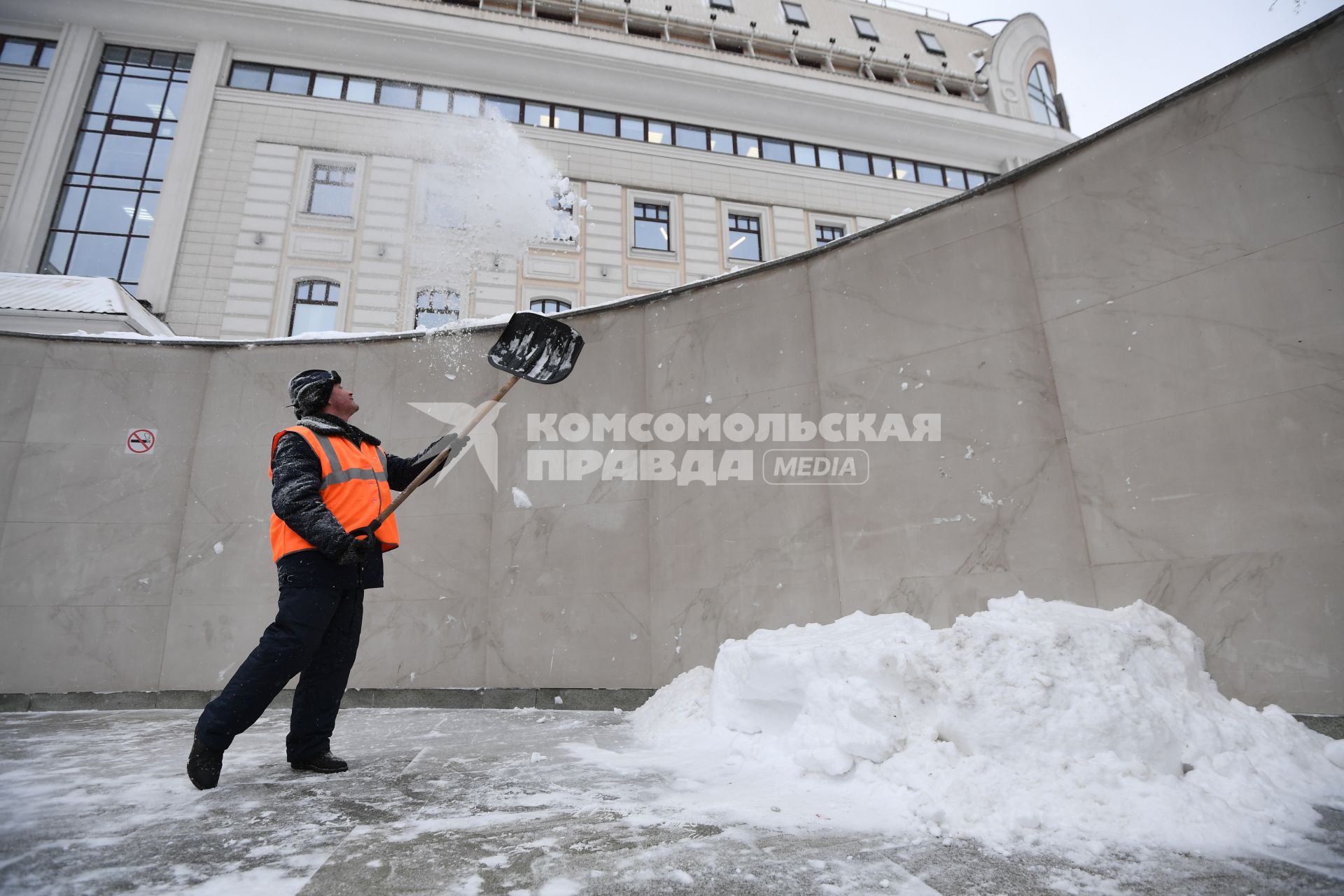 Москва. Дворник скидывает снег из перехода на тротуар.