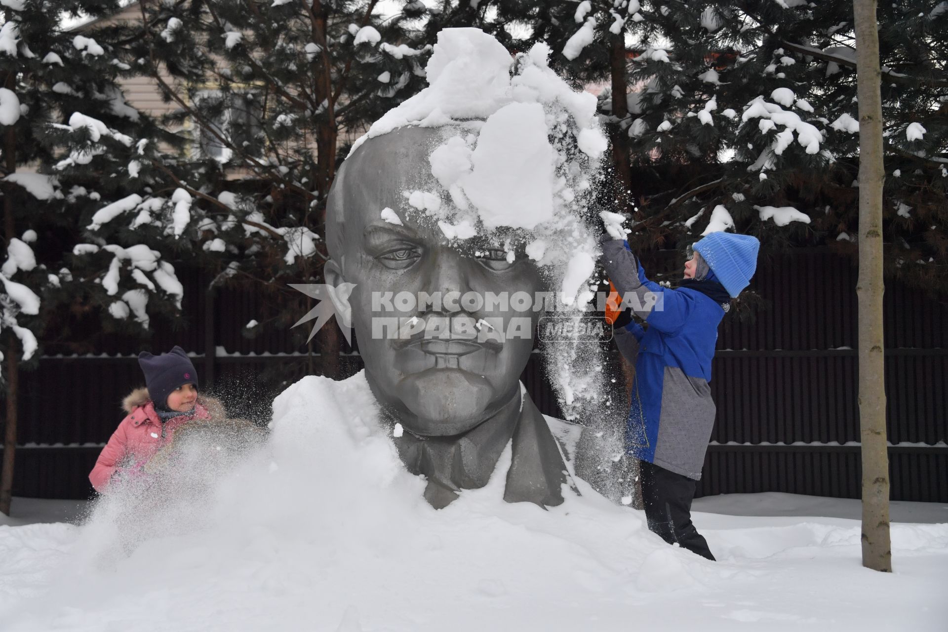 Московская область. Девочки очищают памятник Ленину от снега.