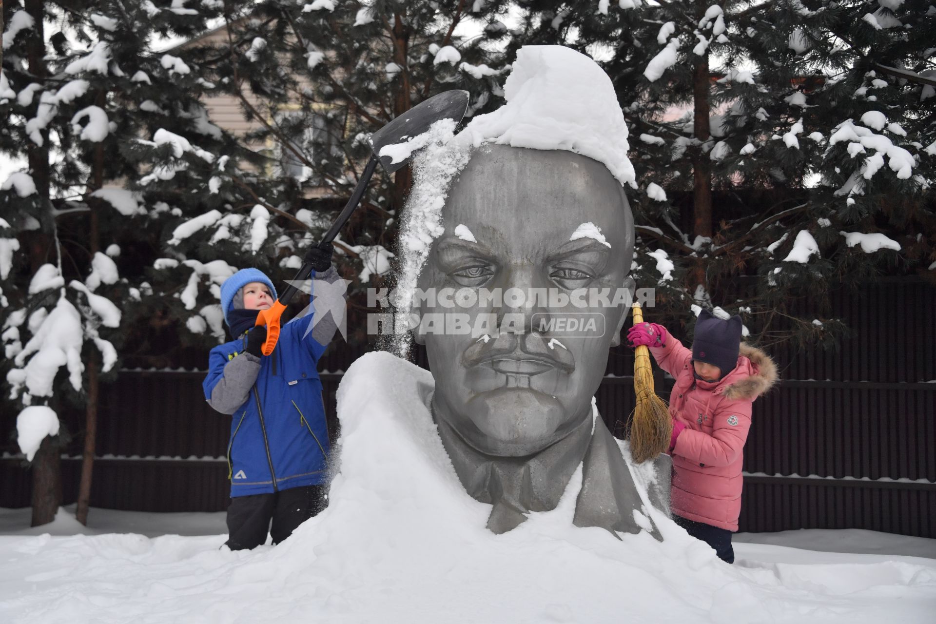 Московская область. Девочки очищают памятник Ленину от снега.