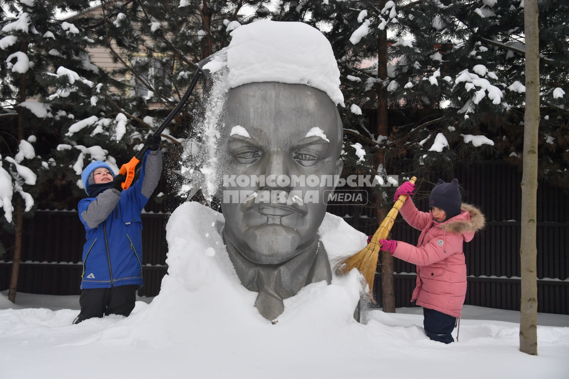 Московская область. Девочки очищают памятник Ленину от снега.