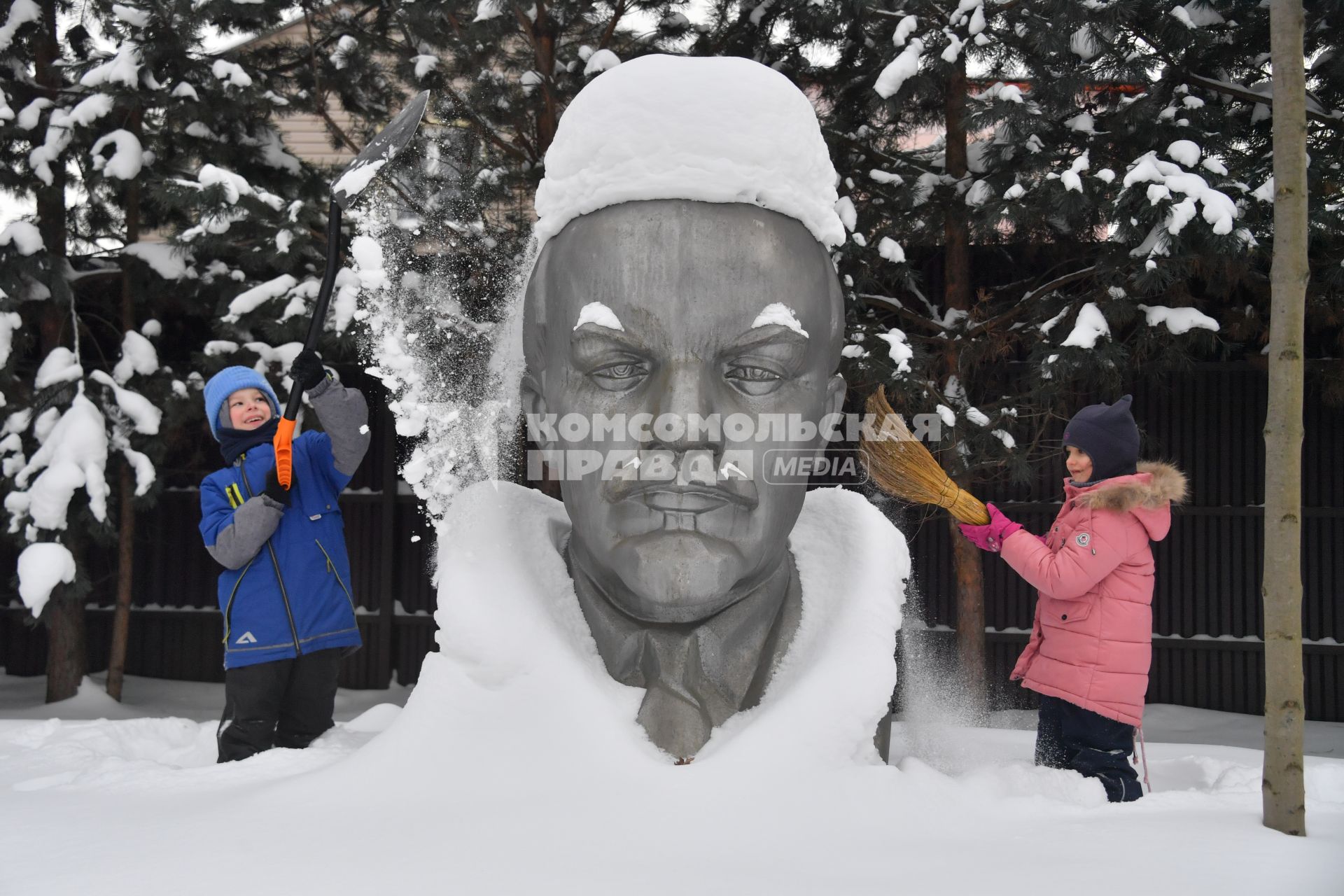 Московская область. Девочки очищают памятник Ленину от снега.