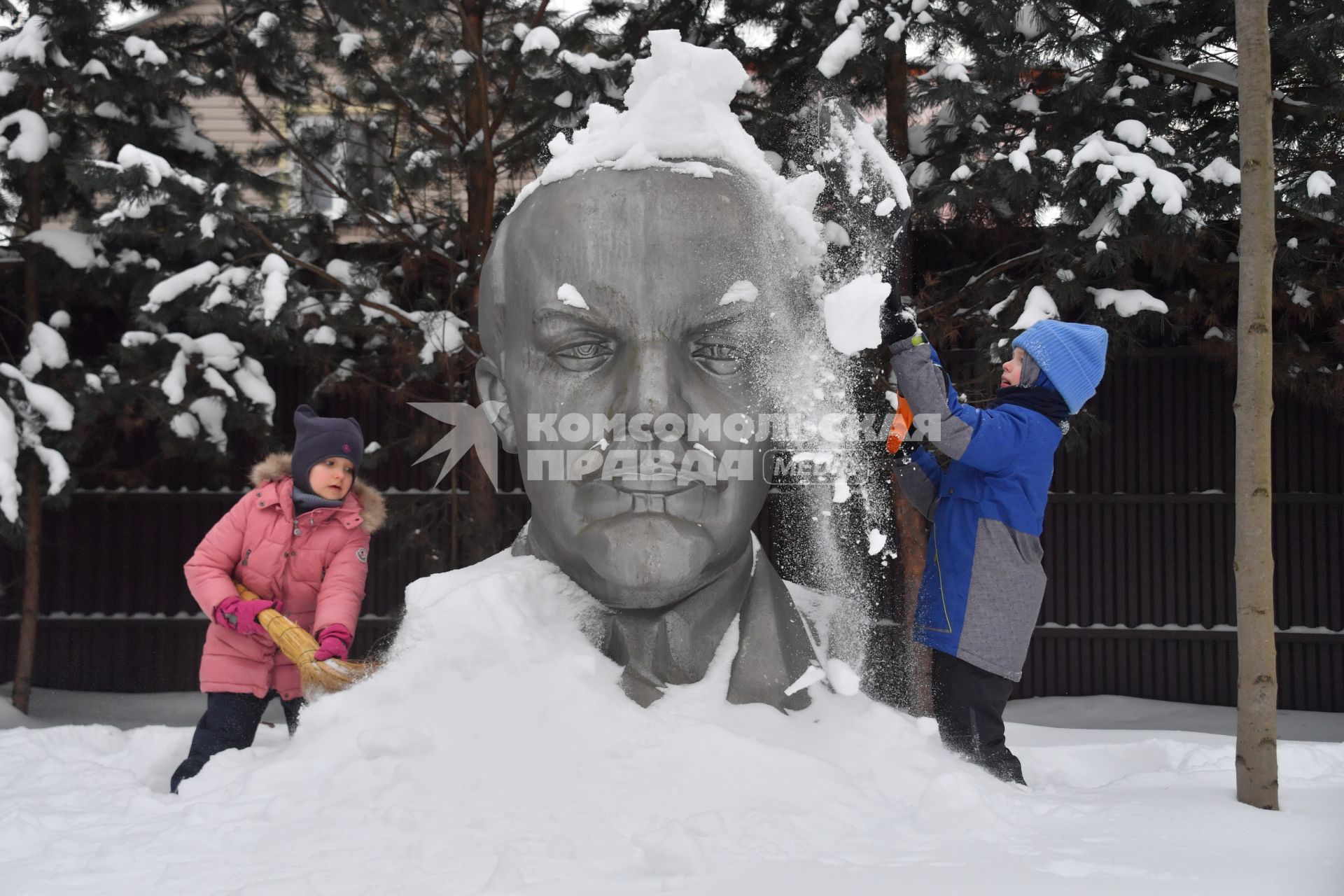 Московская область. Девочки очищают памятник Ленину от снега.