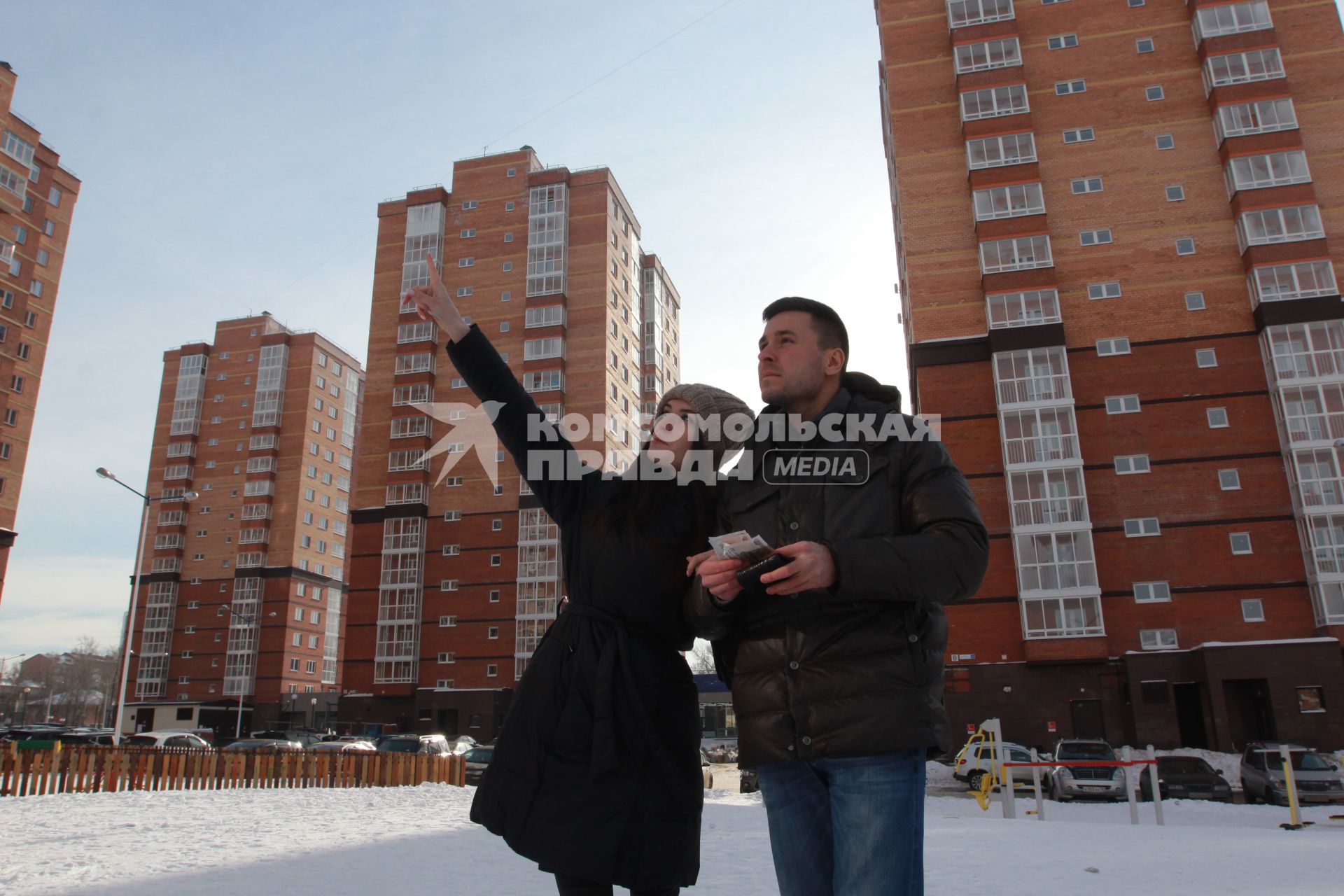 Иркутск. Молодой человек с девушкой осматривают новостройки в новом микрорайоне.