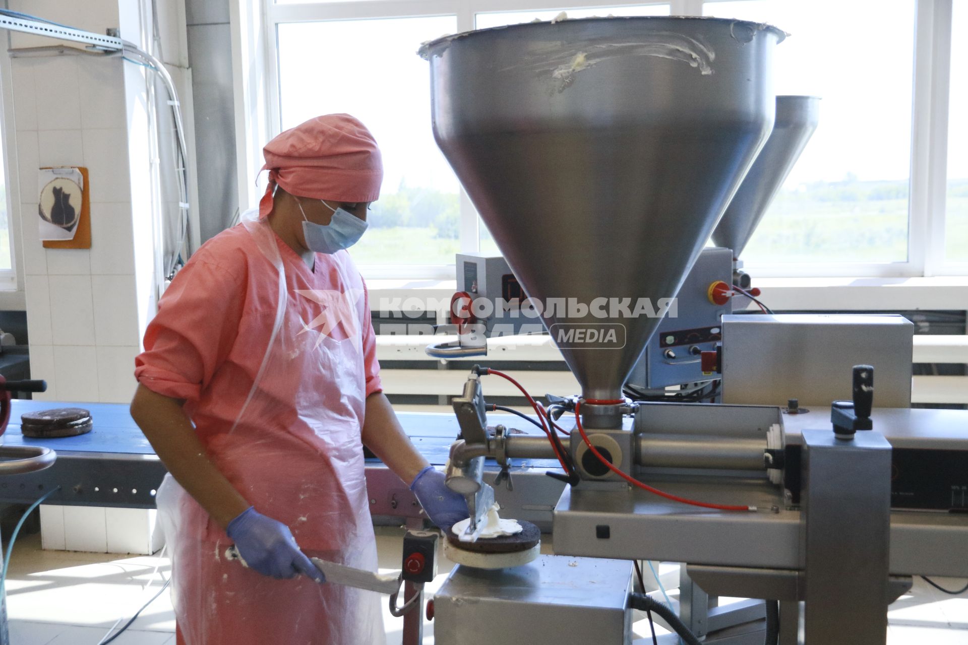 Барнаул. Работница наносит крем на корж с помощью дозатора на кондитерской фабрике.