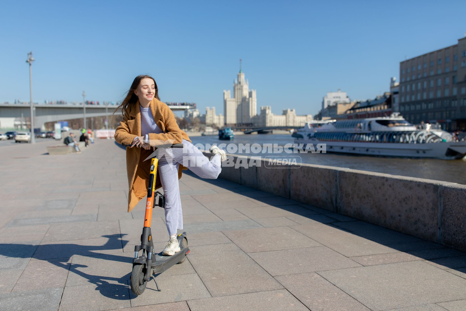 Москва.  Девушка с электросамокатом на Москворецкой набережной.