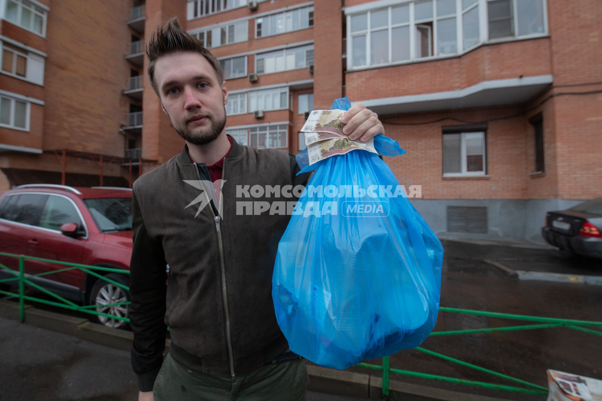 Москва. Корреспондент `Комсомольской правды` Андрей Абрамов держит в руке пакет с мусором и деньги.