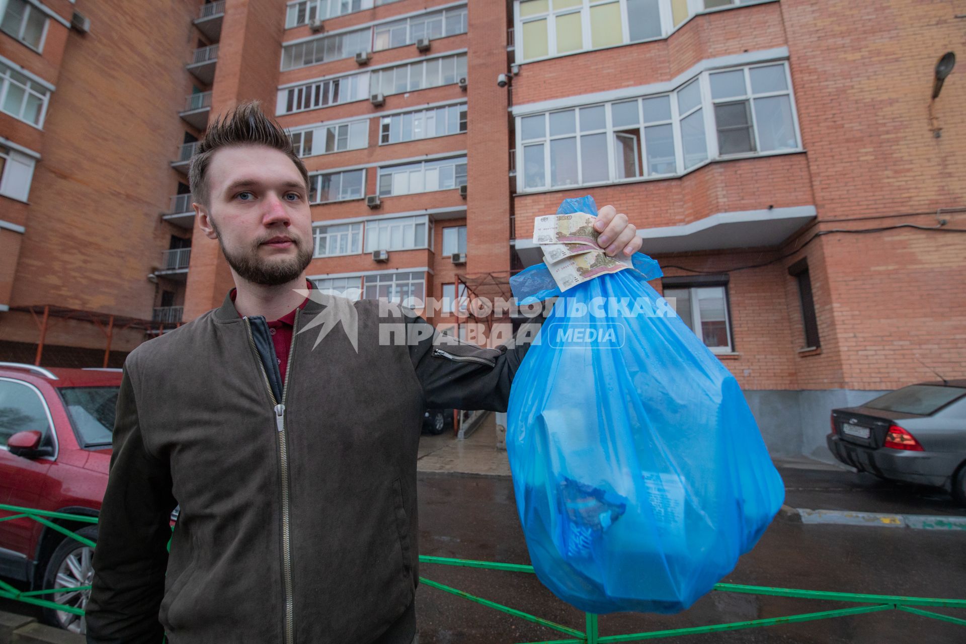 Москва. Корреспондент `Комсомольской правды` Андрей Абрамов держит в руке пакет с мусором и деньги.