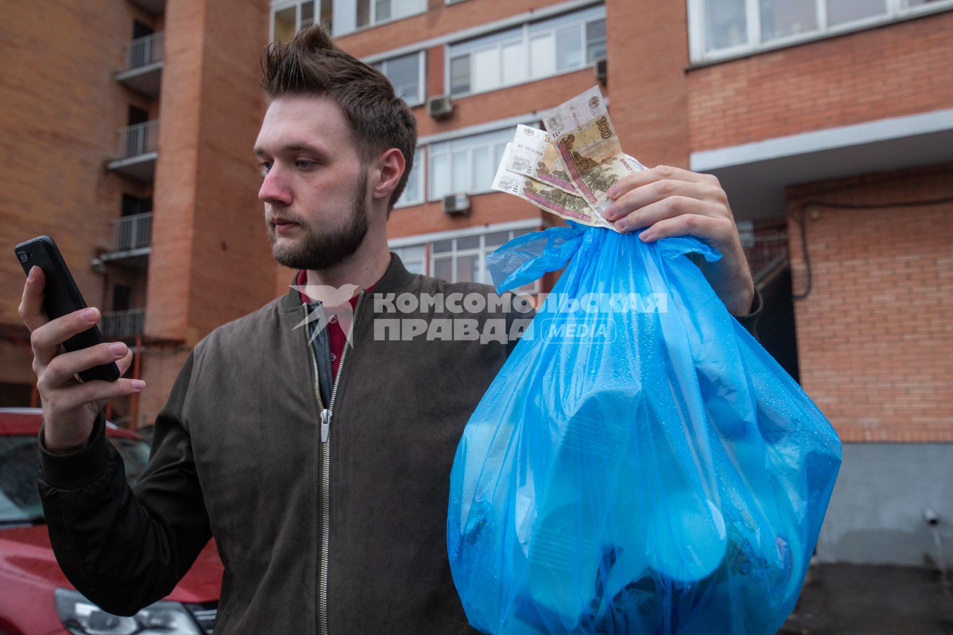 Москва. Корреспондент `Комсомольской правды` Андрей Абрамов держит в руке пакет с мусором и деньги.