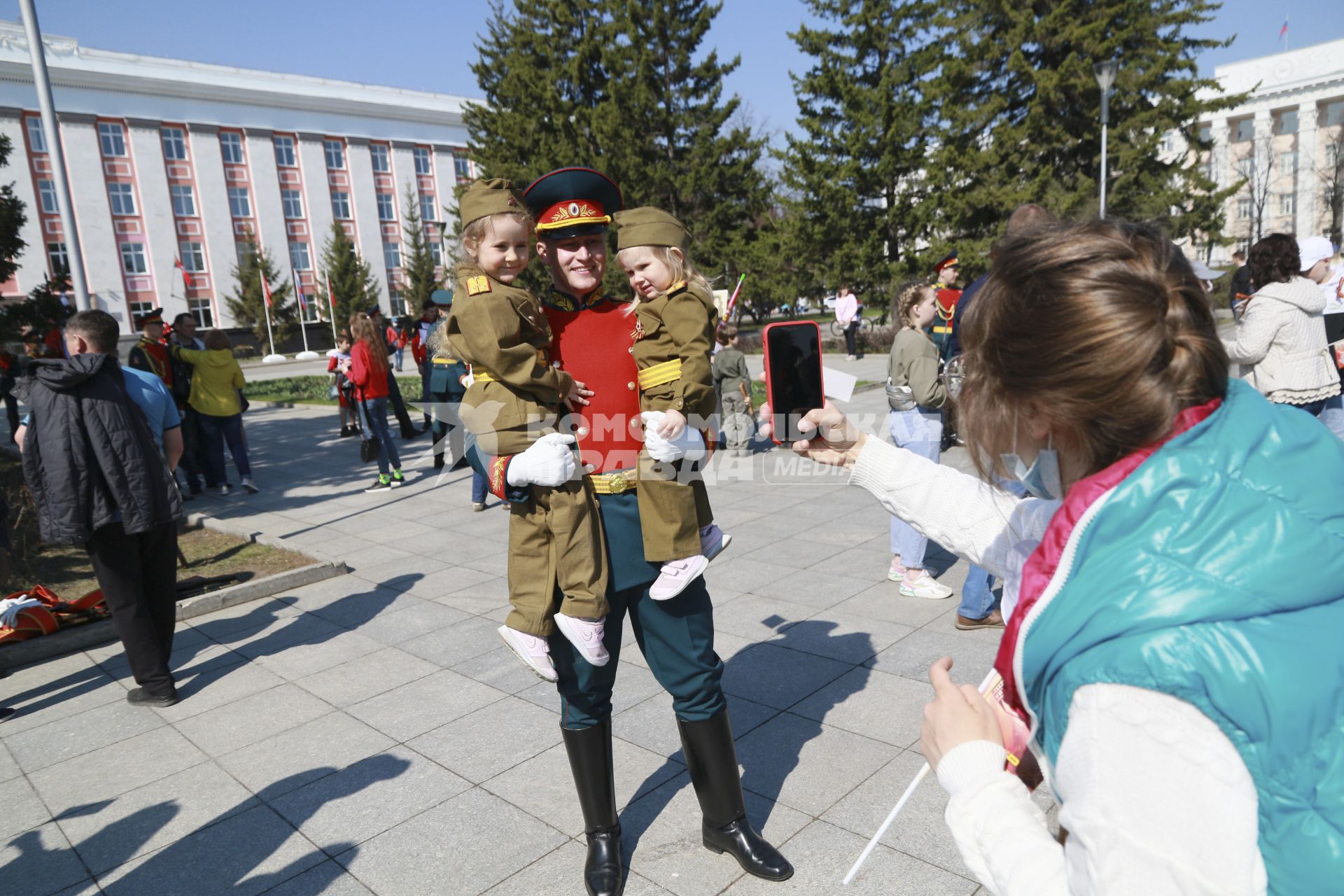 Барнаул. Военнослужащий держит на руках девочек, одетых в военную форму во время празднования Дня Победы.