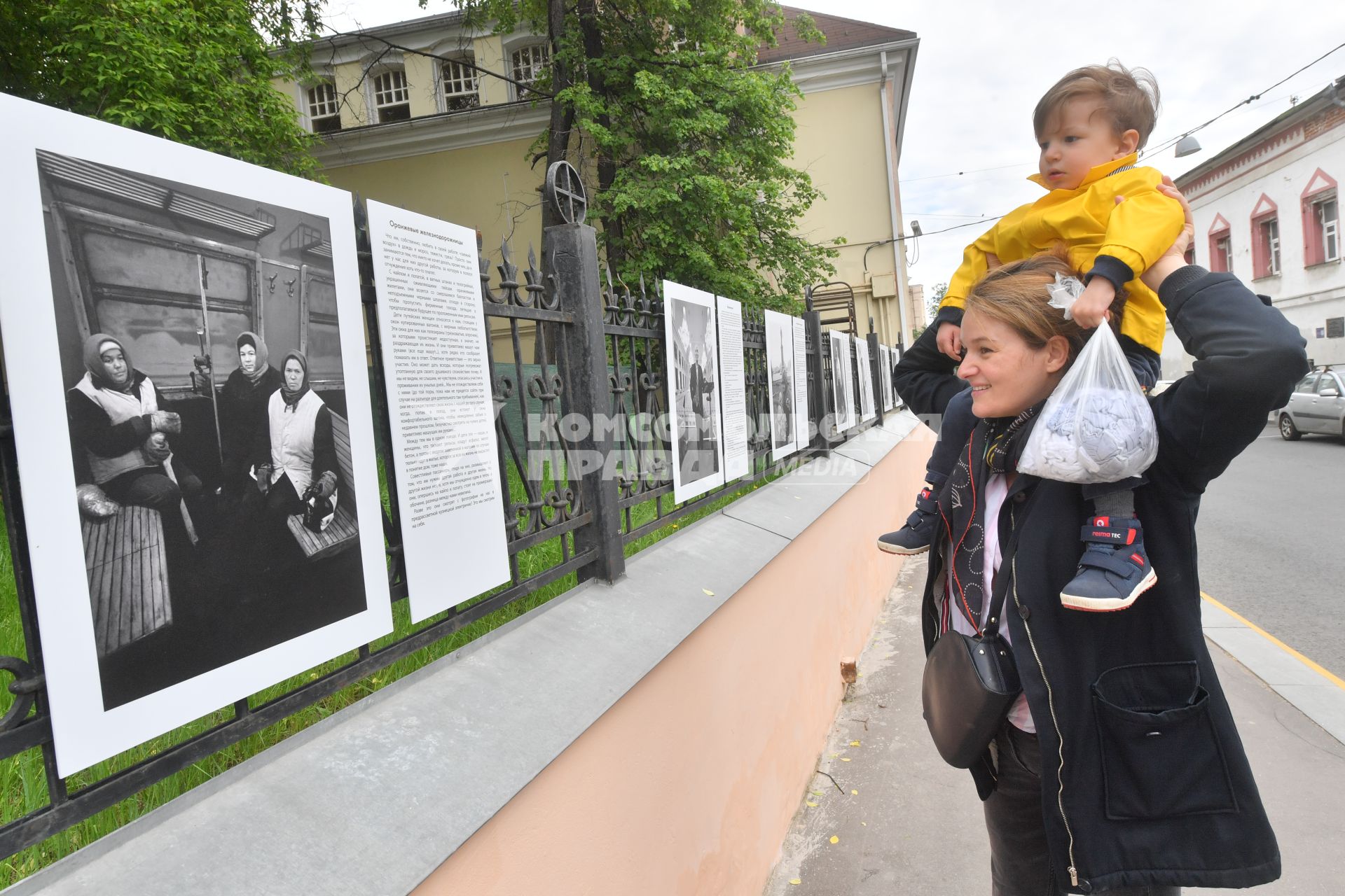 Москва.  Прохожие у фотографий  на выставке под открытым небом -  проект `Люди` журналиста и фотографа Юрия Роста , у храма Живоначальной Троицы в Хохлах .