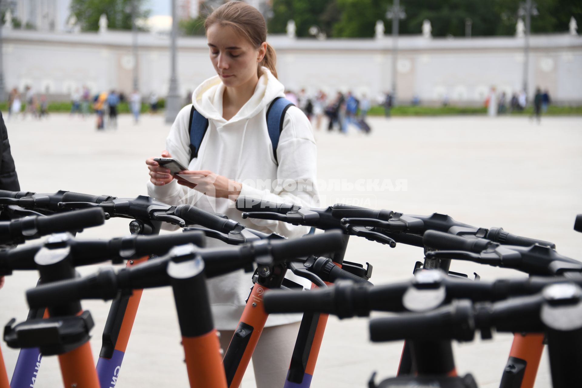 Москва.  Посетители берут самокаты на пункте проката электросамокатов на ВДНХ.