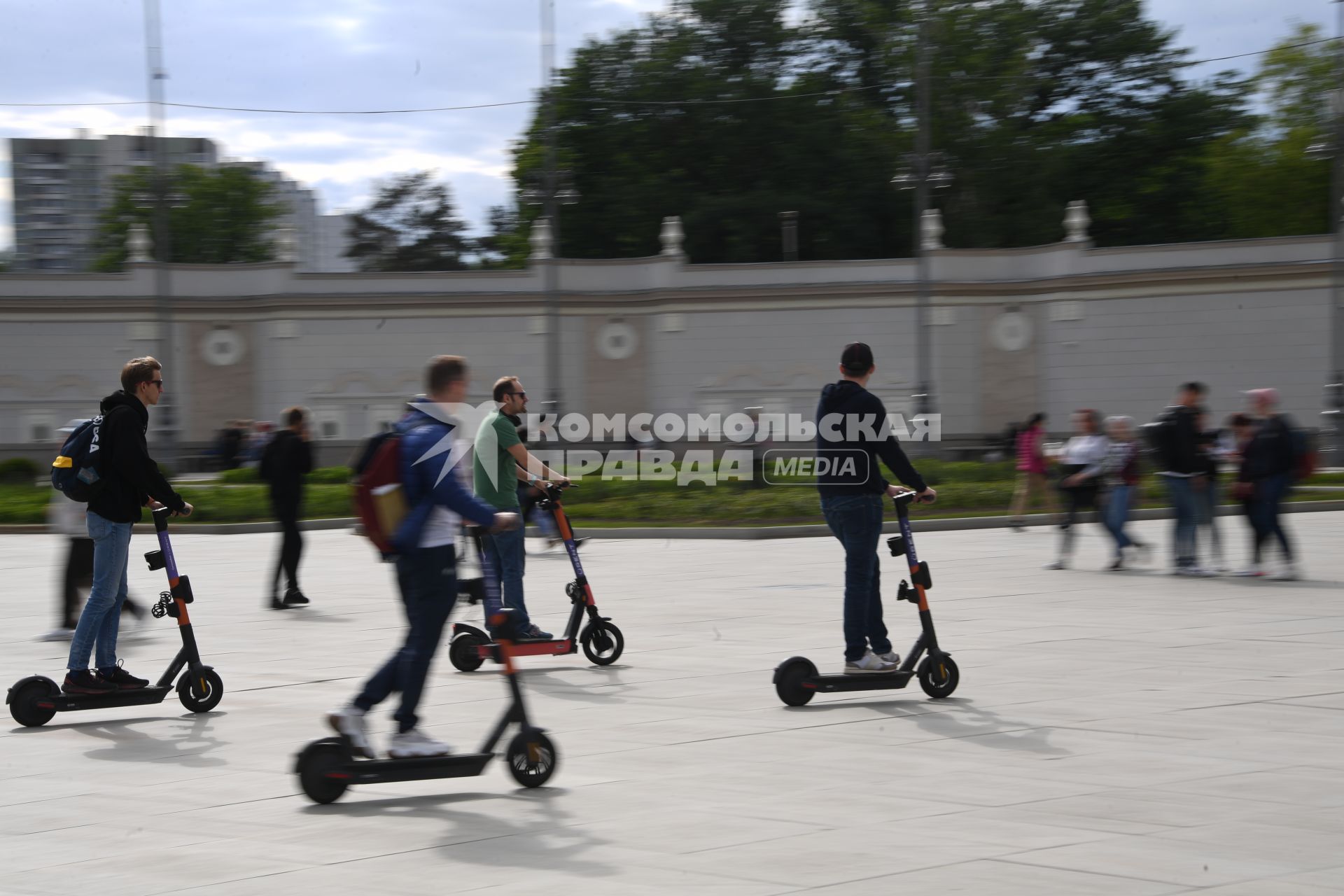 Москва. Молодые люди катаются  на электросамокате  на ВДНХ.