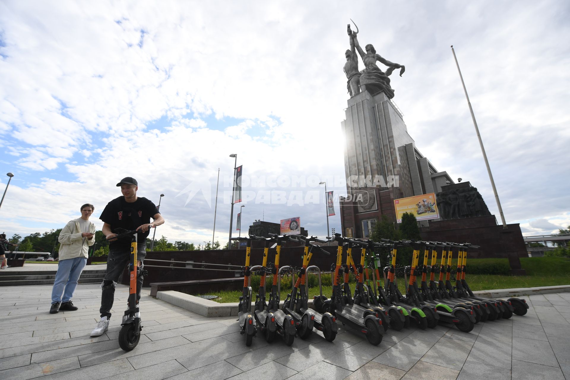 Москва.  Посетители берут самокаты на пункте проката электросамокатов на ВДНХ.