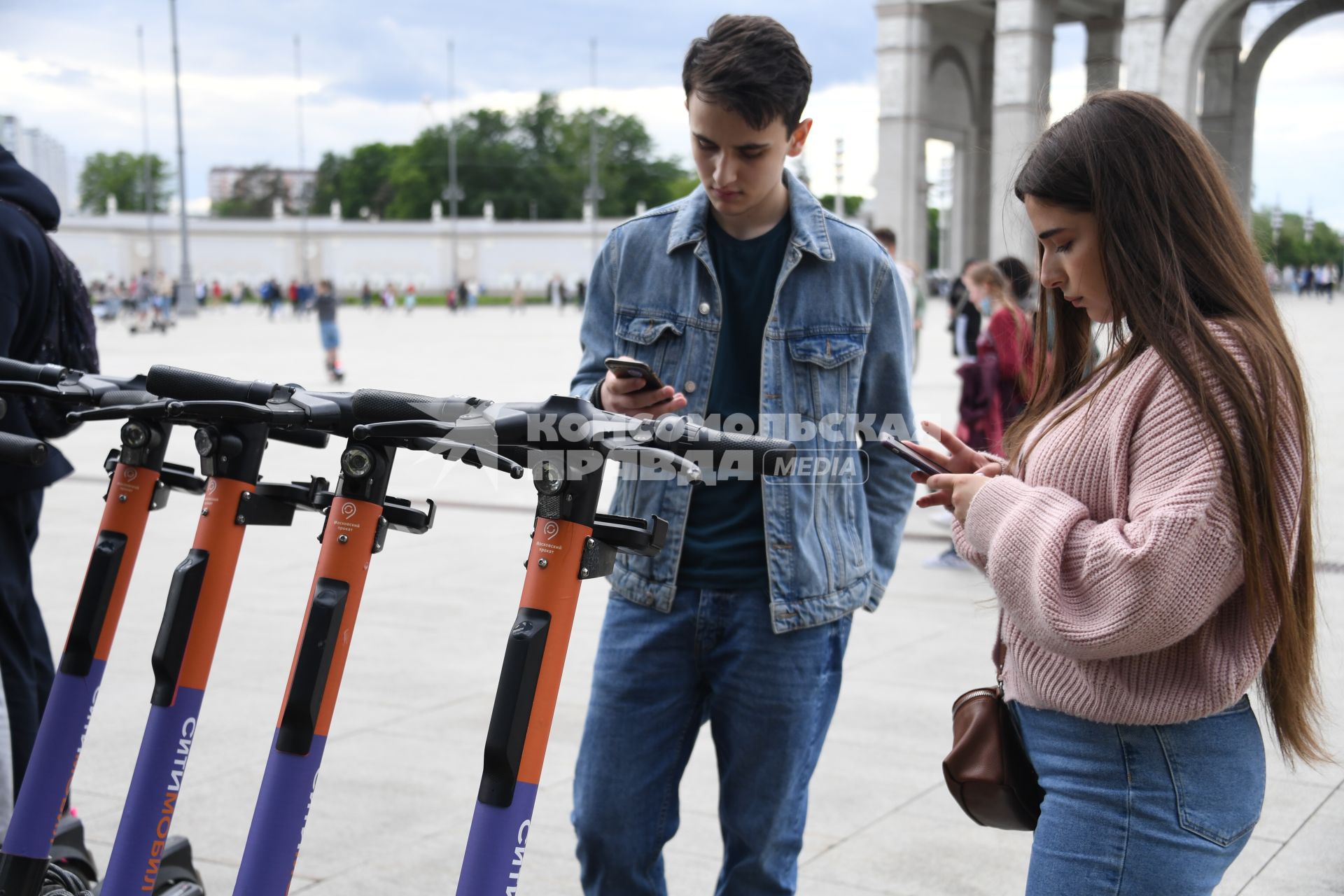 Москва.  Посетители берут самокаты на пункте проката электросамокатов на ВДНХ.